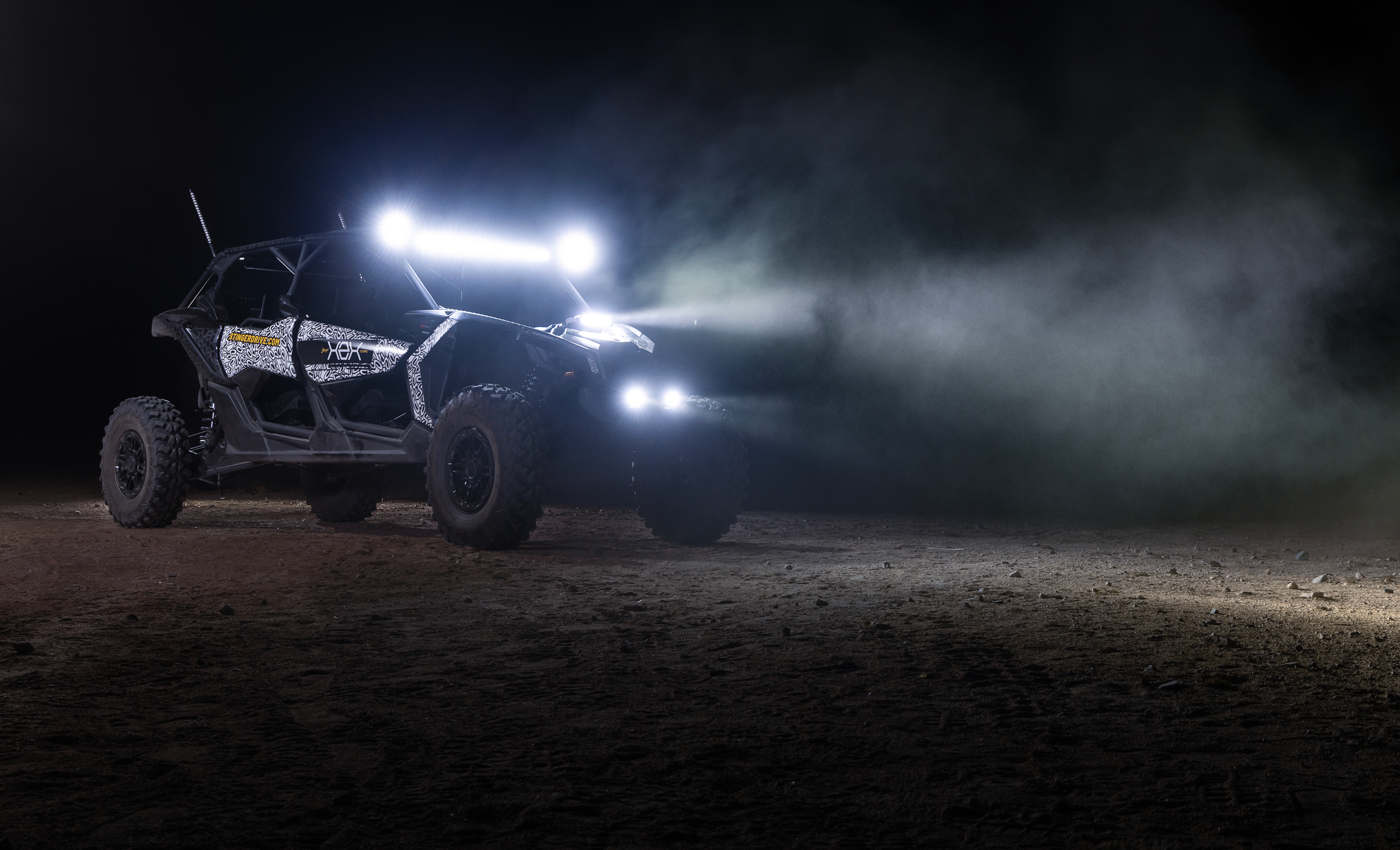 Off-road vehicle with illuminated lights on a dark, dusty terrain