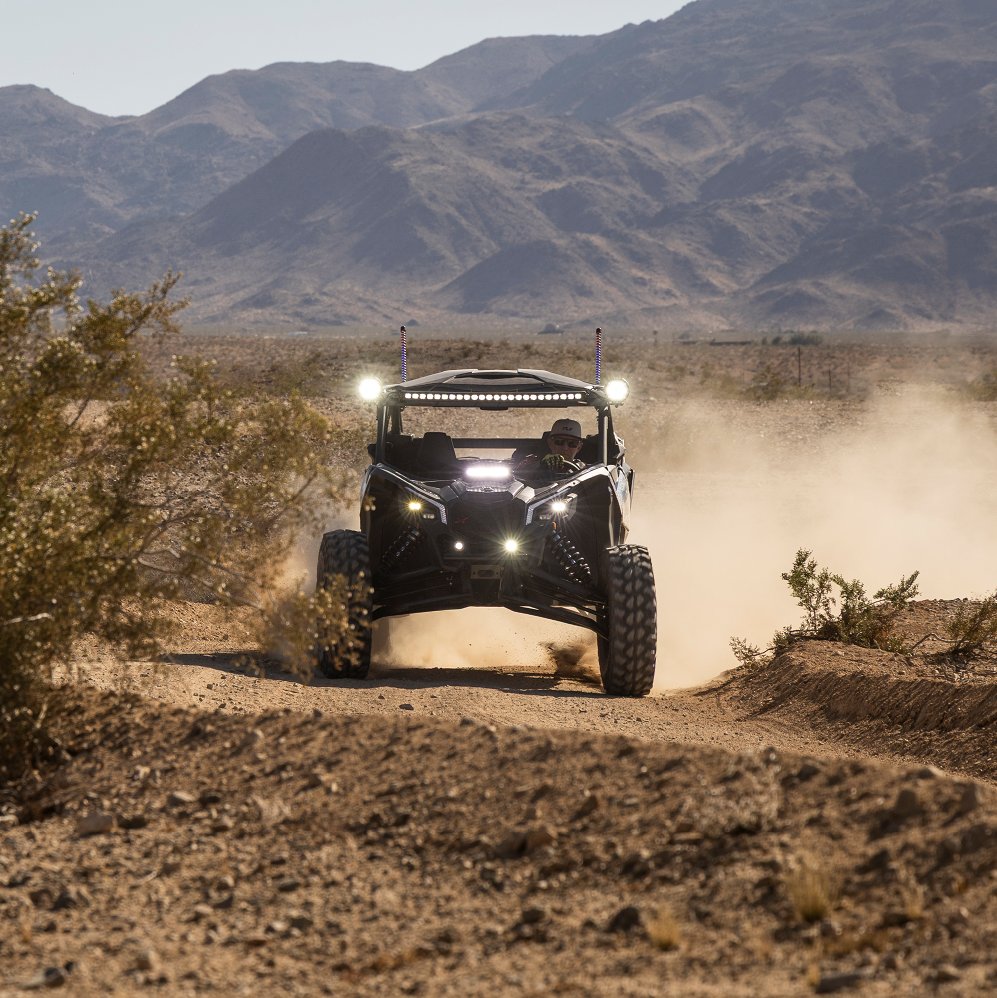 Off-road vehicle driving on a dirt road with mountains in the background