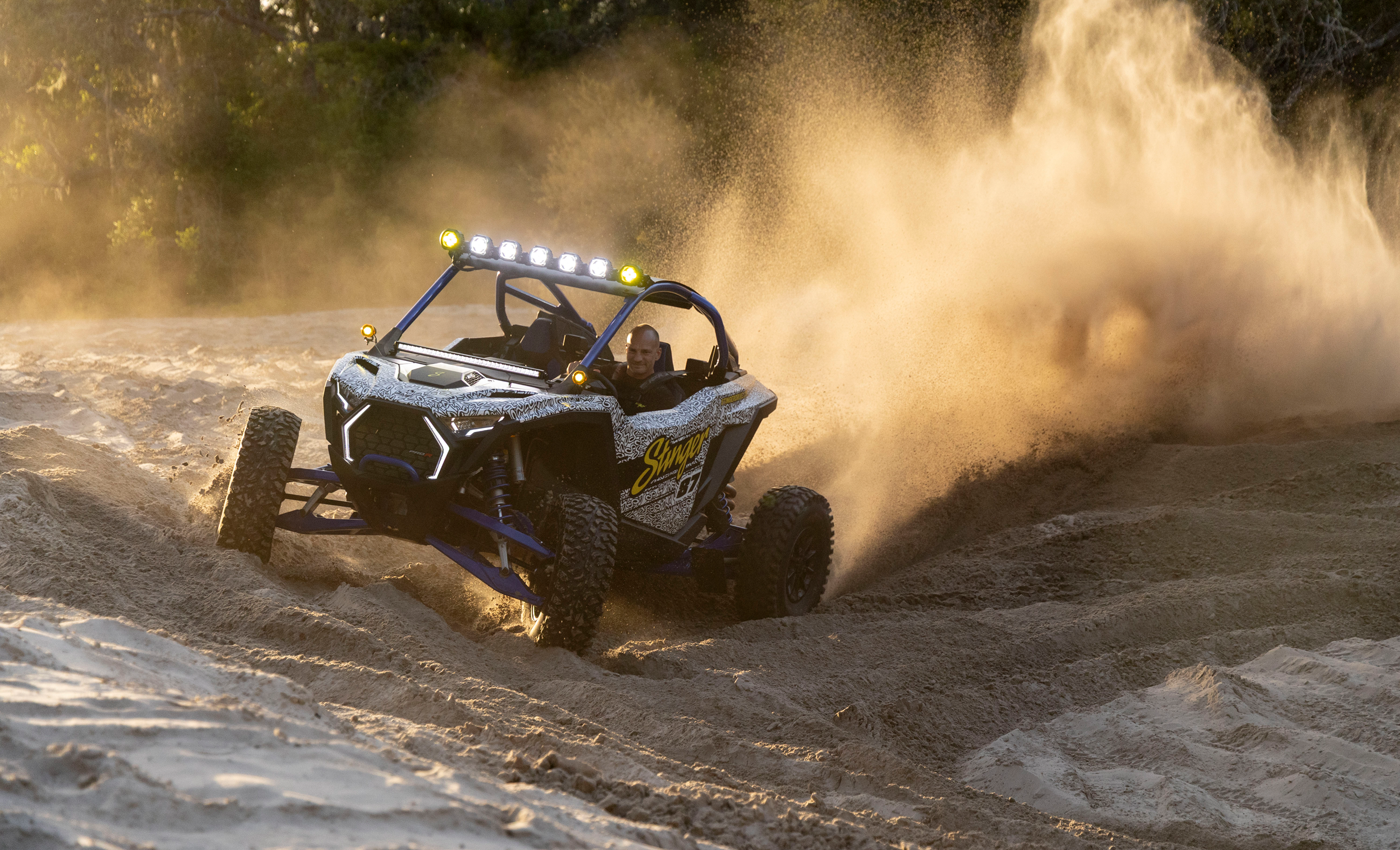 Off-road vehicle driving on a dirt track with dust in the air