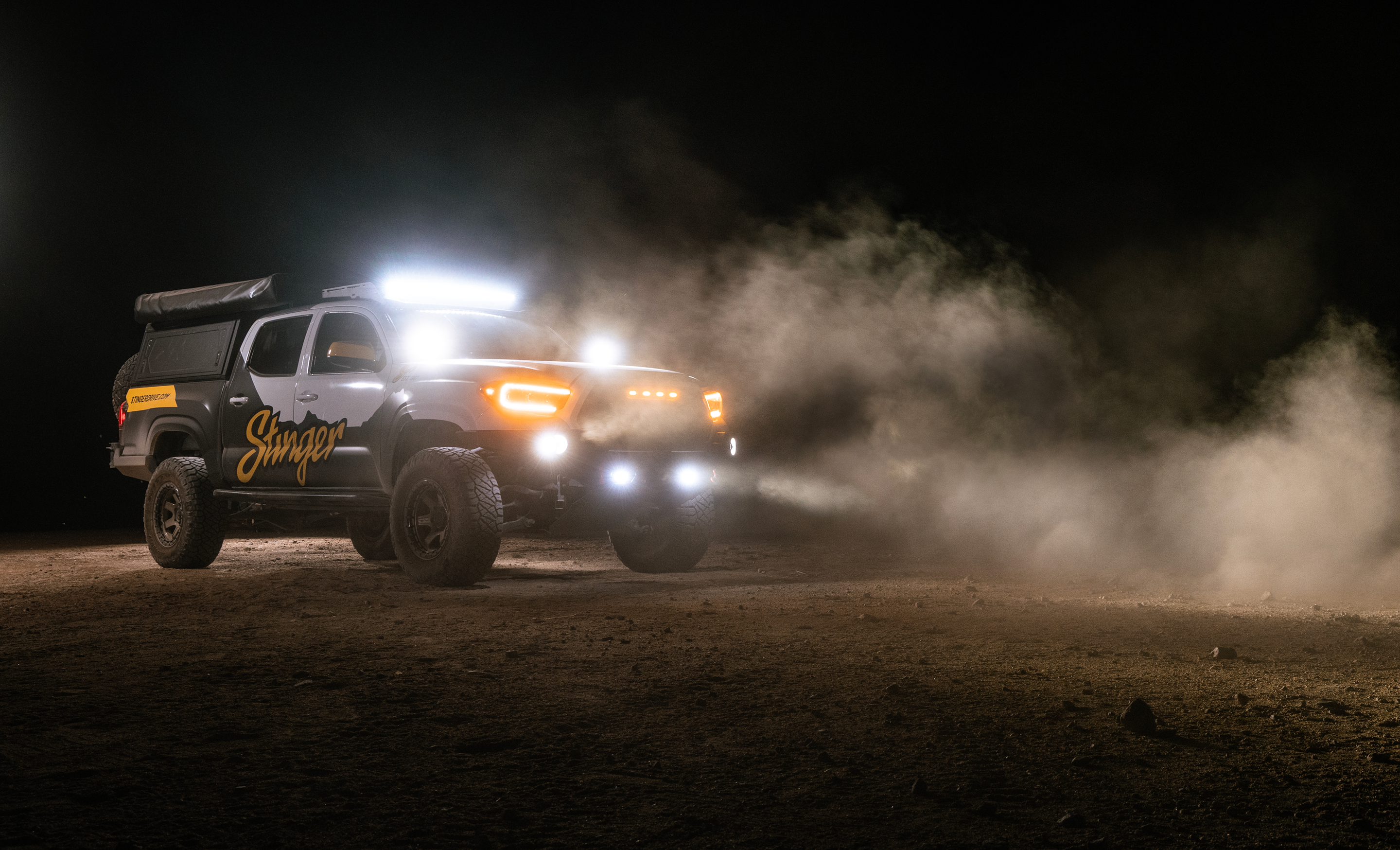 Off-road vehicle driving on a dirt road at night with dust in the air