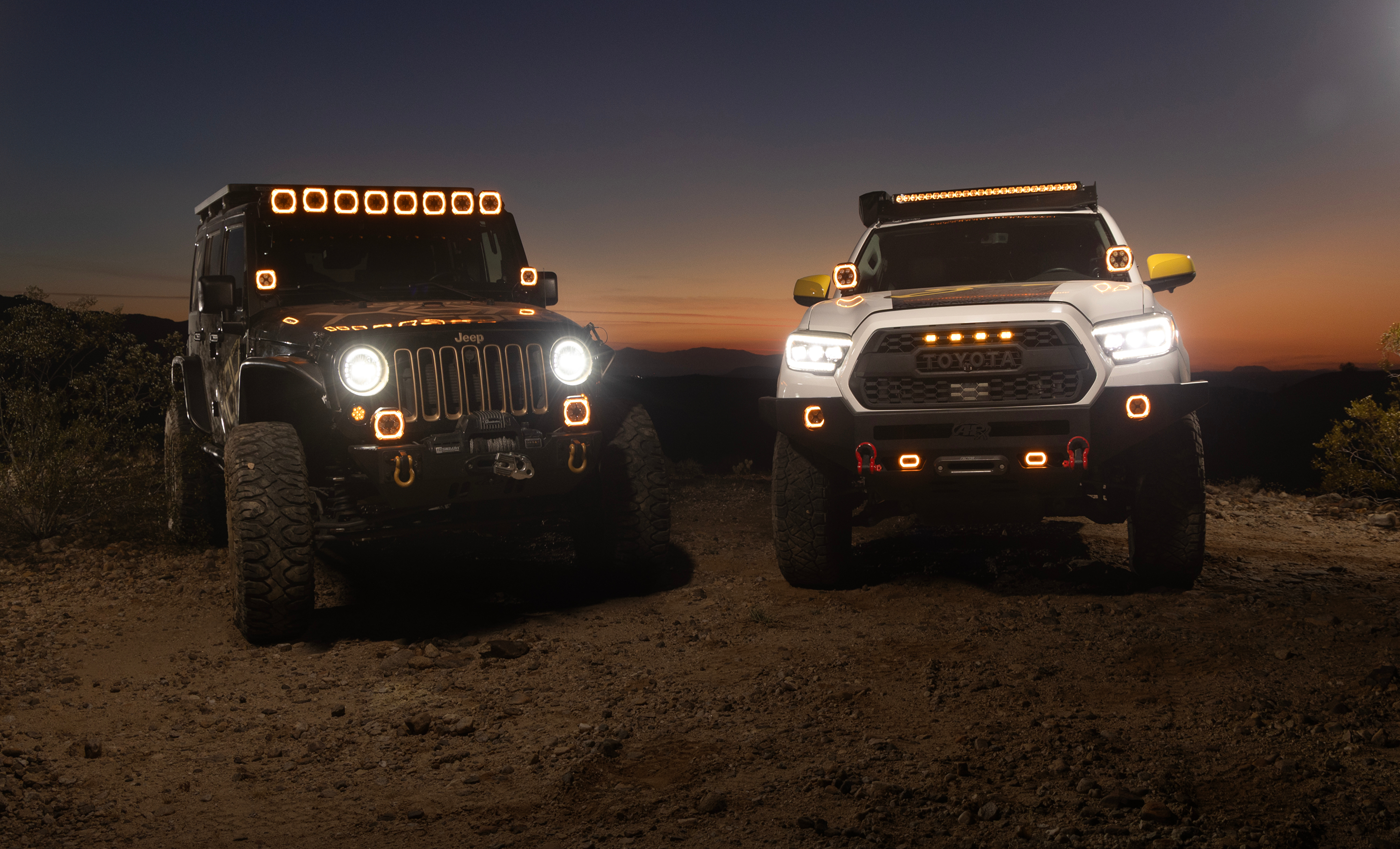 Two off-road vehicles on a dirt road at sunset.