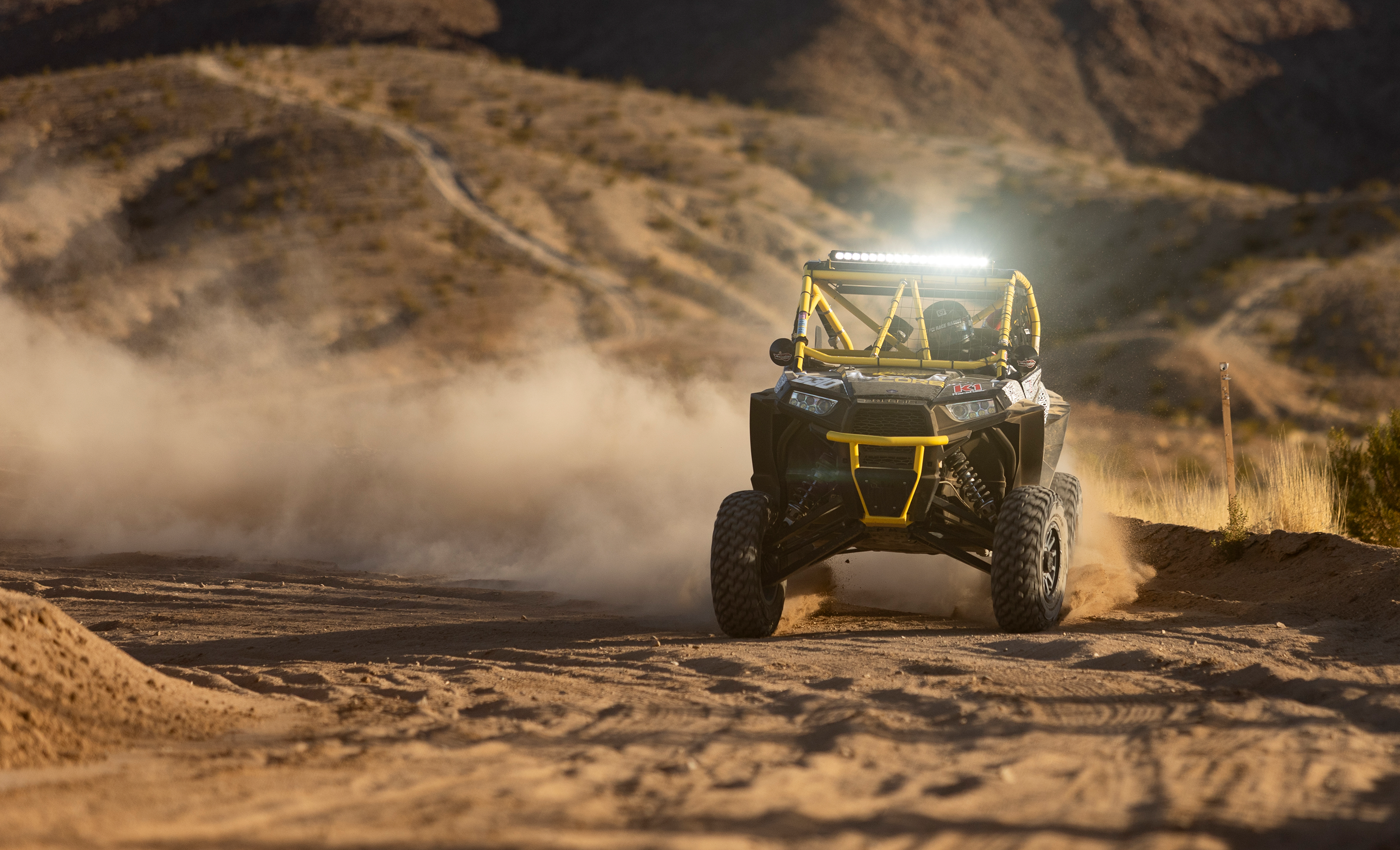 Off-road vehicle driving on a dirt road with mountains in the background