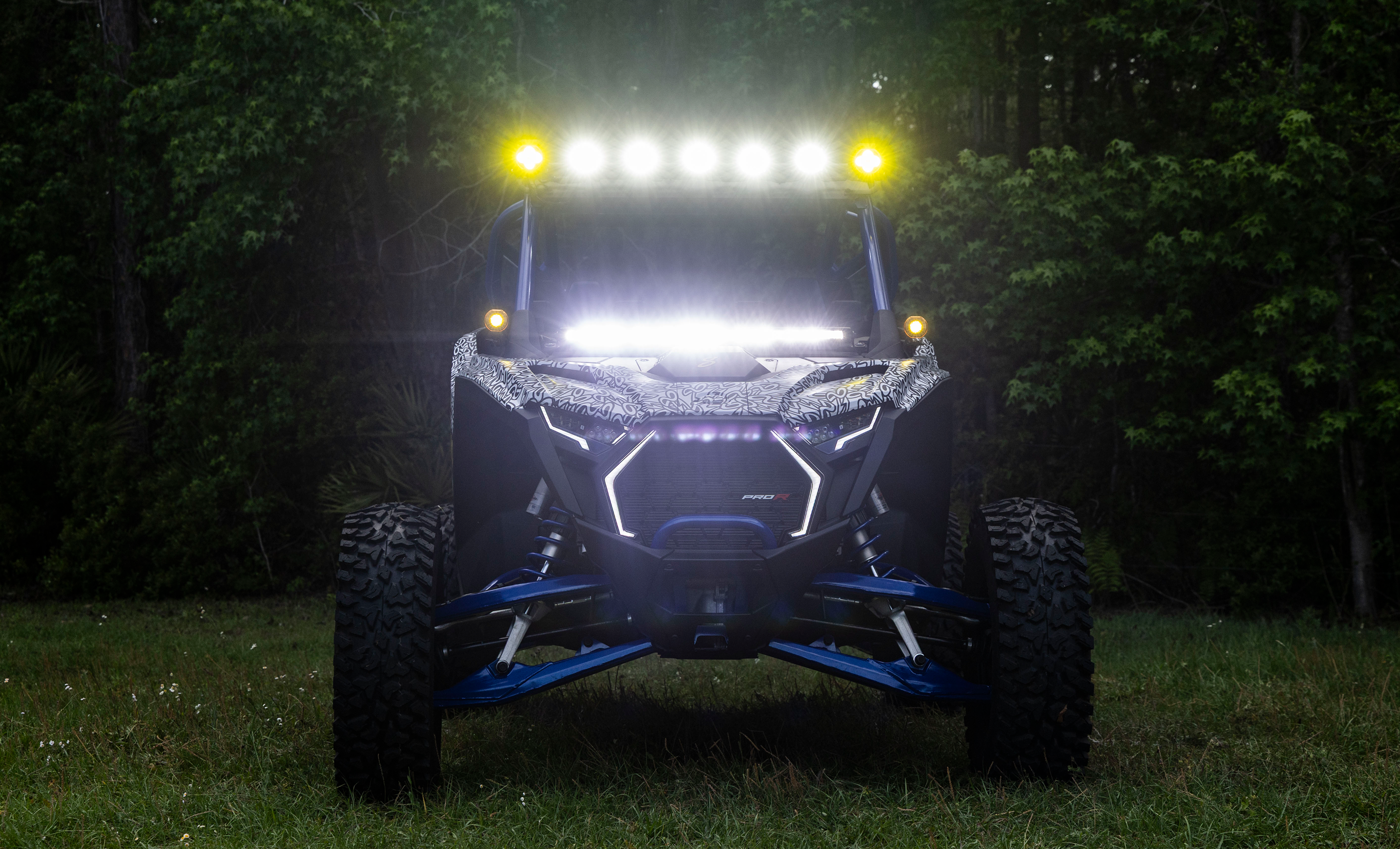 Off-road vehicle with bright lights on a dark forested area