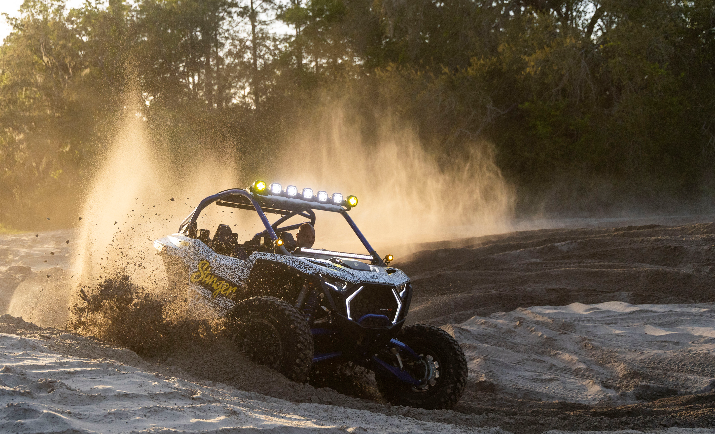 Off-road vehicle driving on a dirt track with dust in the air