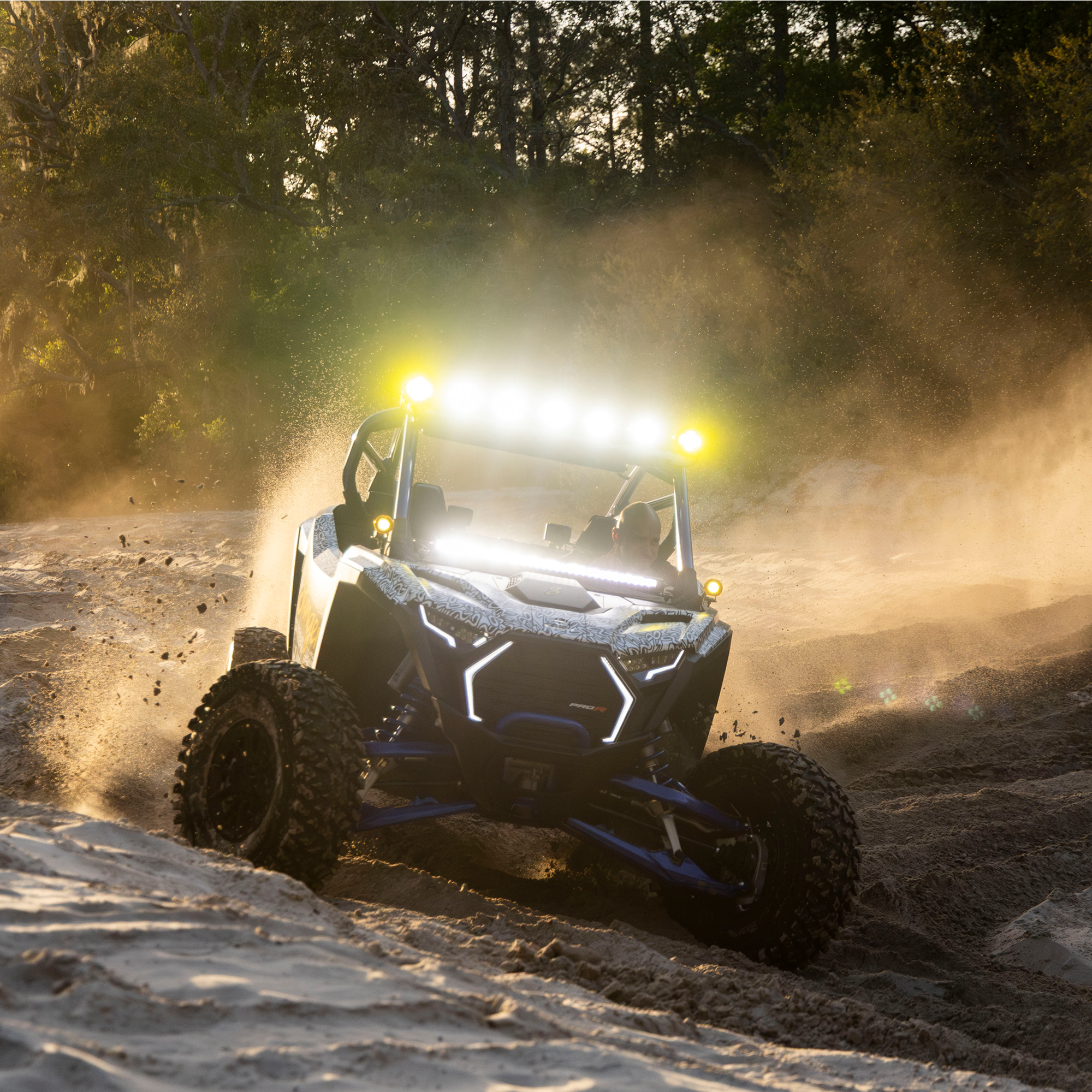 Off-road vehicle driving on a dirt track with trees in the background