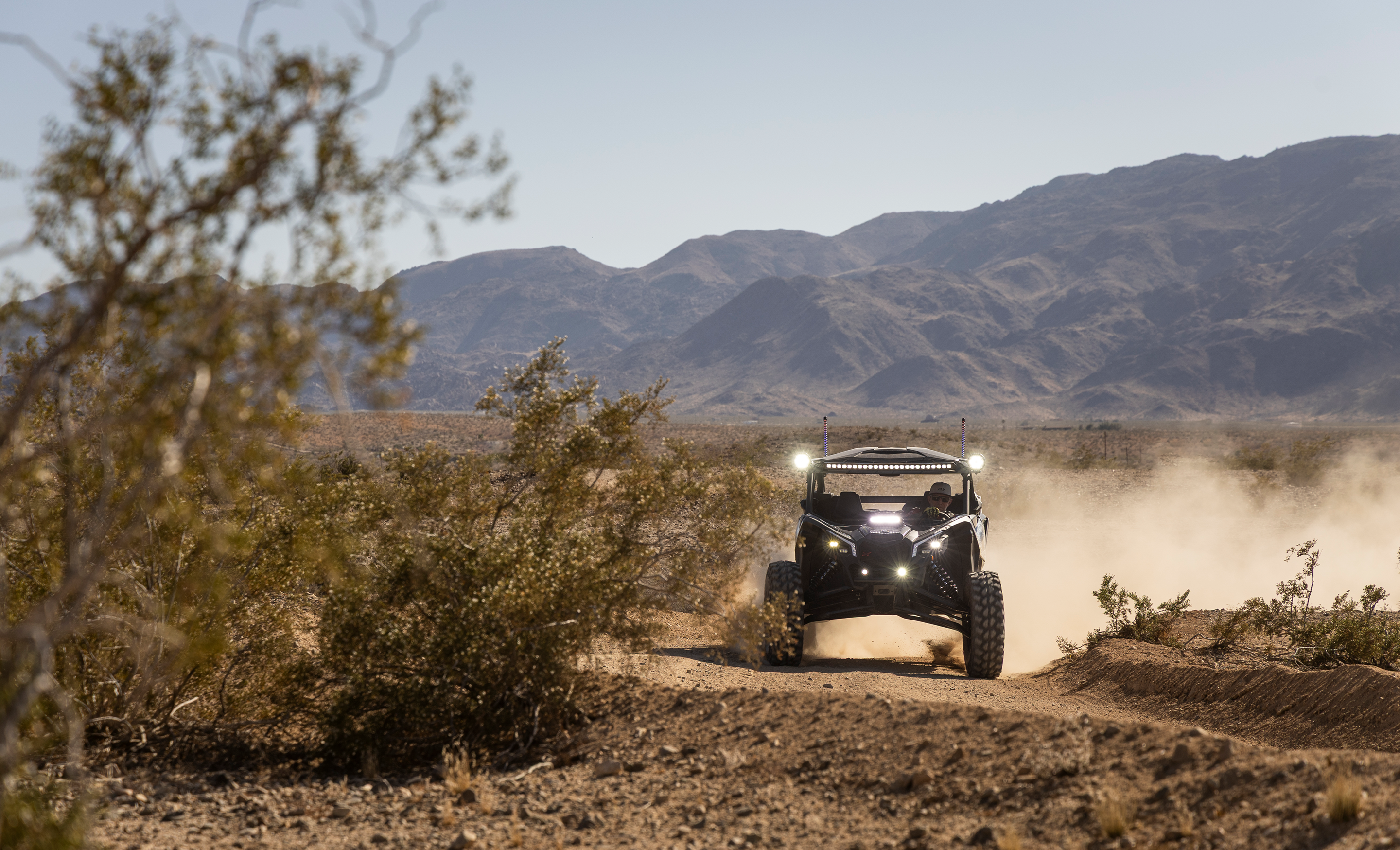 Off-road vehicle driving on a dirt road with mountains in the background