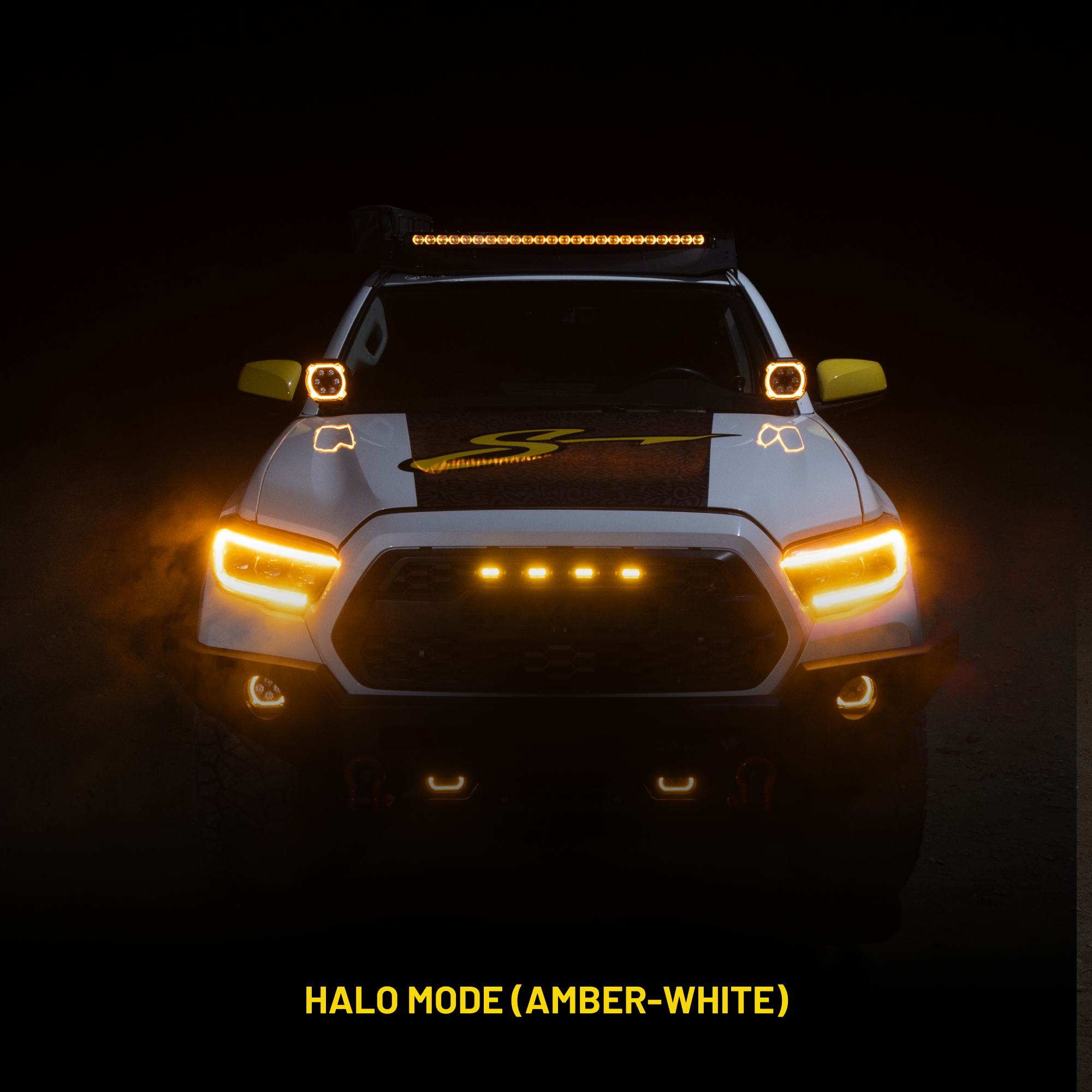 Front view of a vehicle with illuminated headlights and roof lights on a dark background.