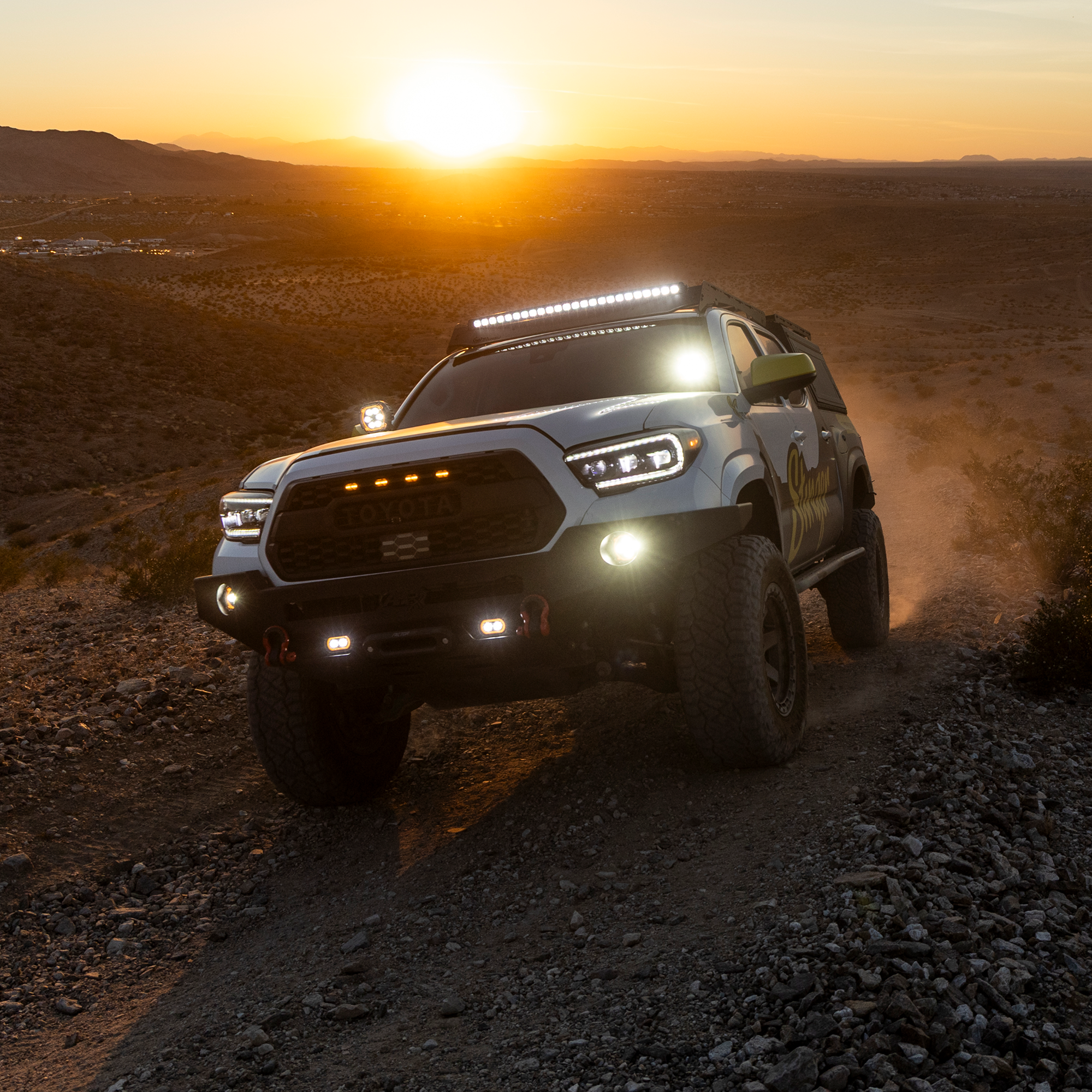 Off-road vehicle driving on a dirt road with sunset in the background