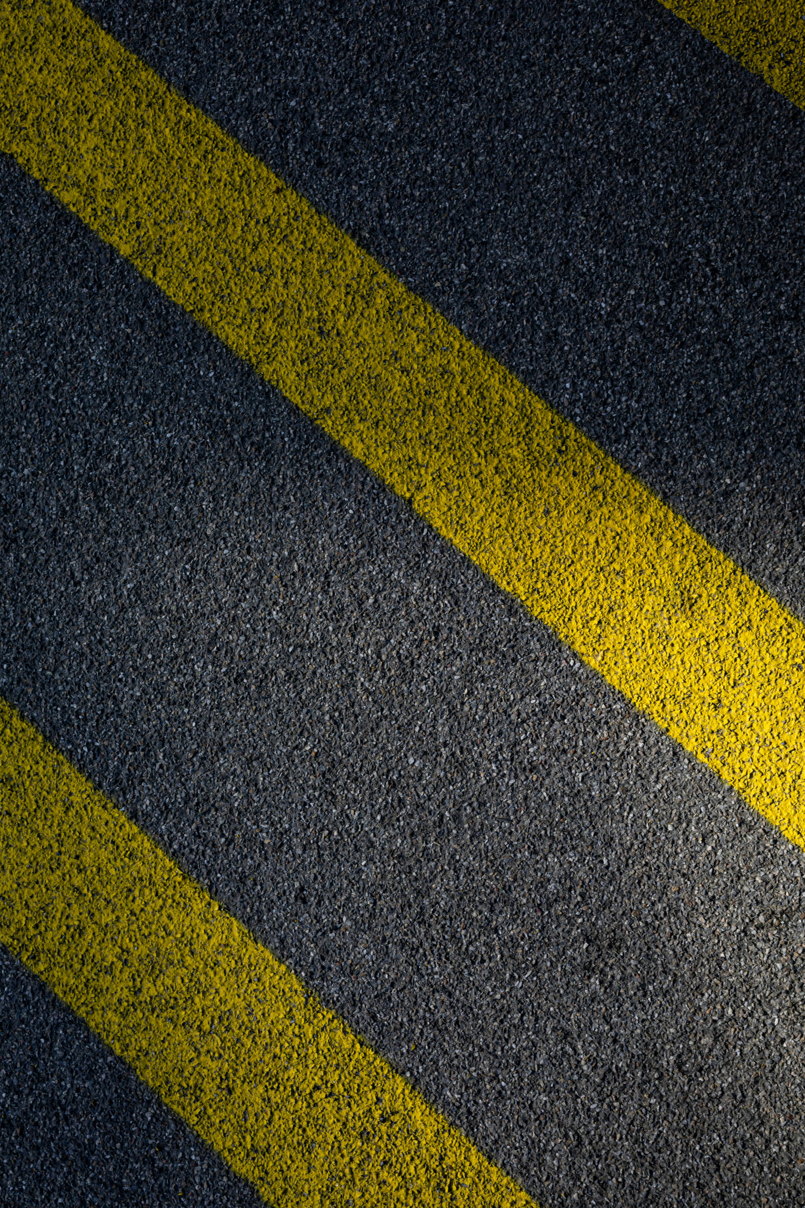 Two parallel yellow painted lines on grey asphalt road surface