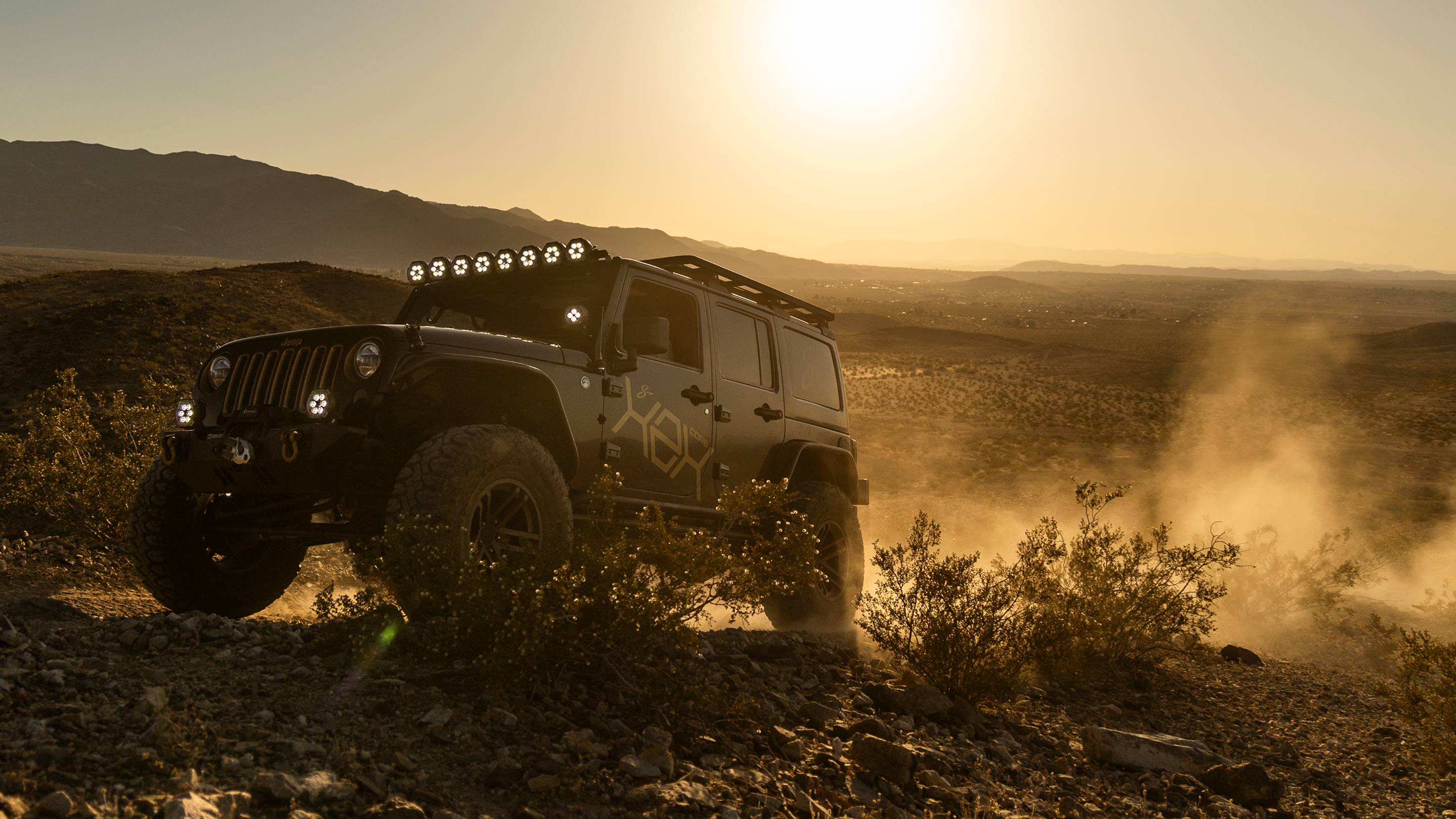 Jeep driving on a dirt road with a sunset in the background