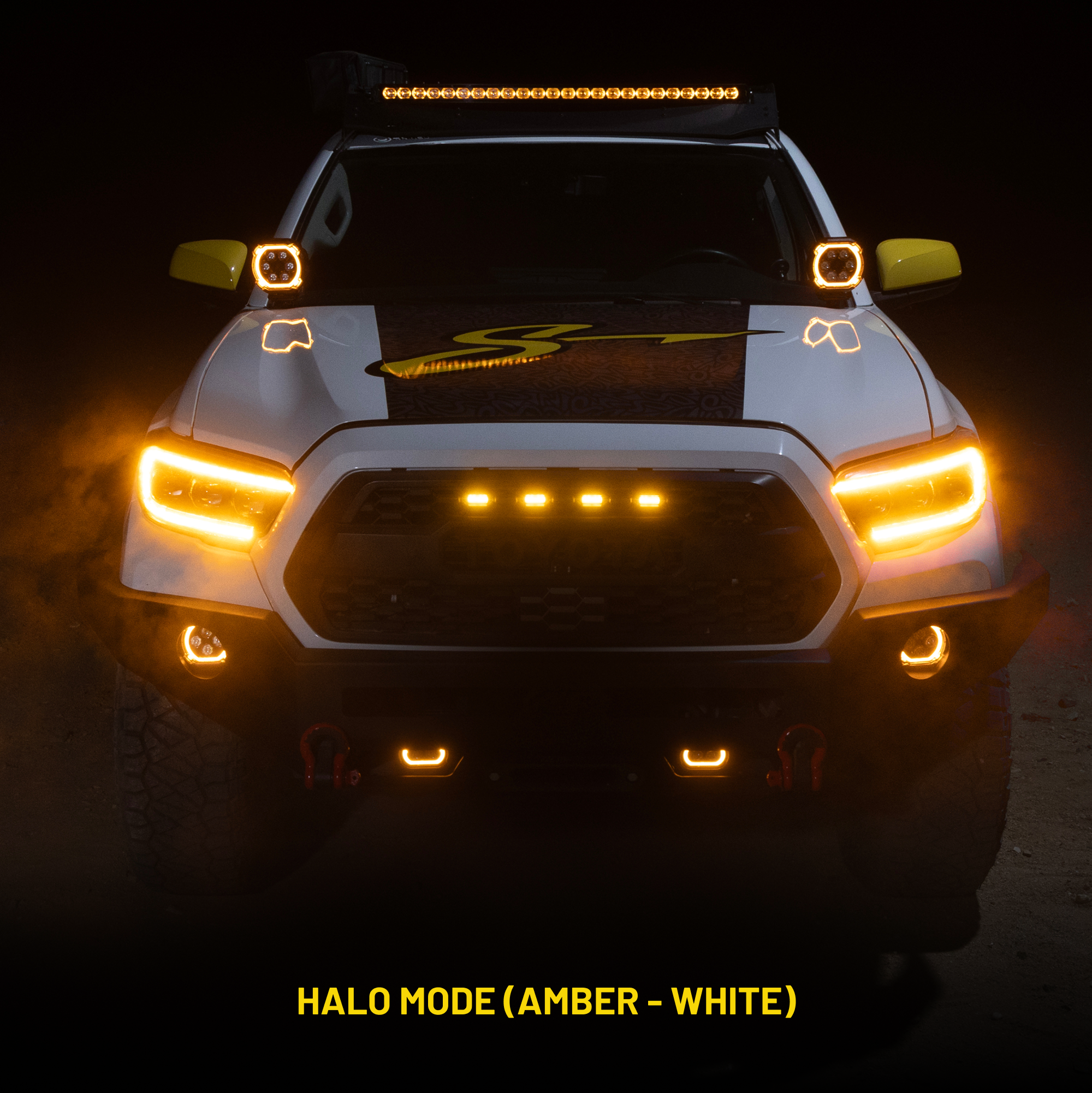 Front view of white truck with illuminated amber halo headlights and auxiliary lights in dark setting