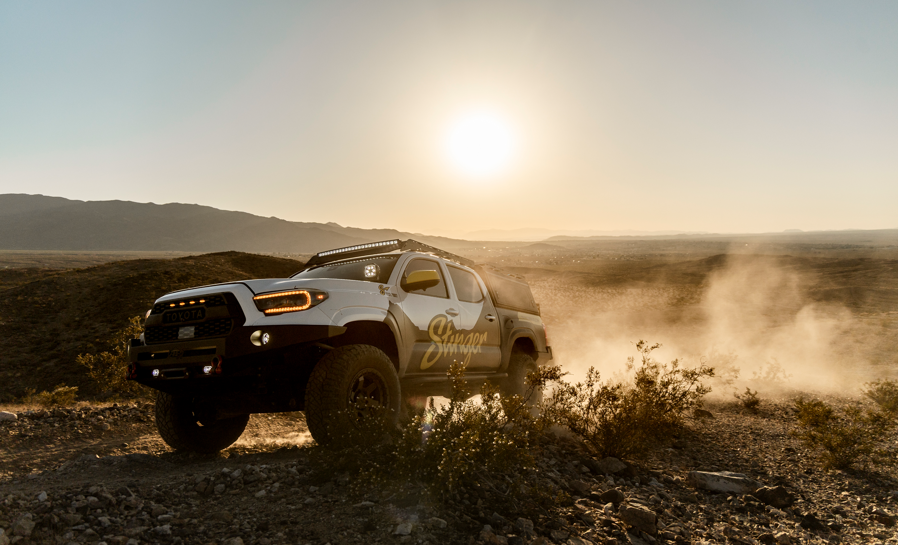 SUV driving on a dirt road with a sunset in the background