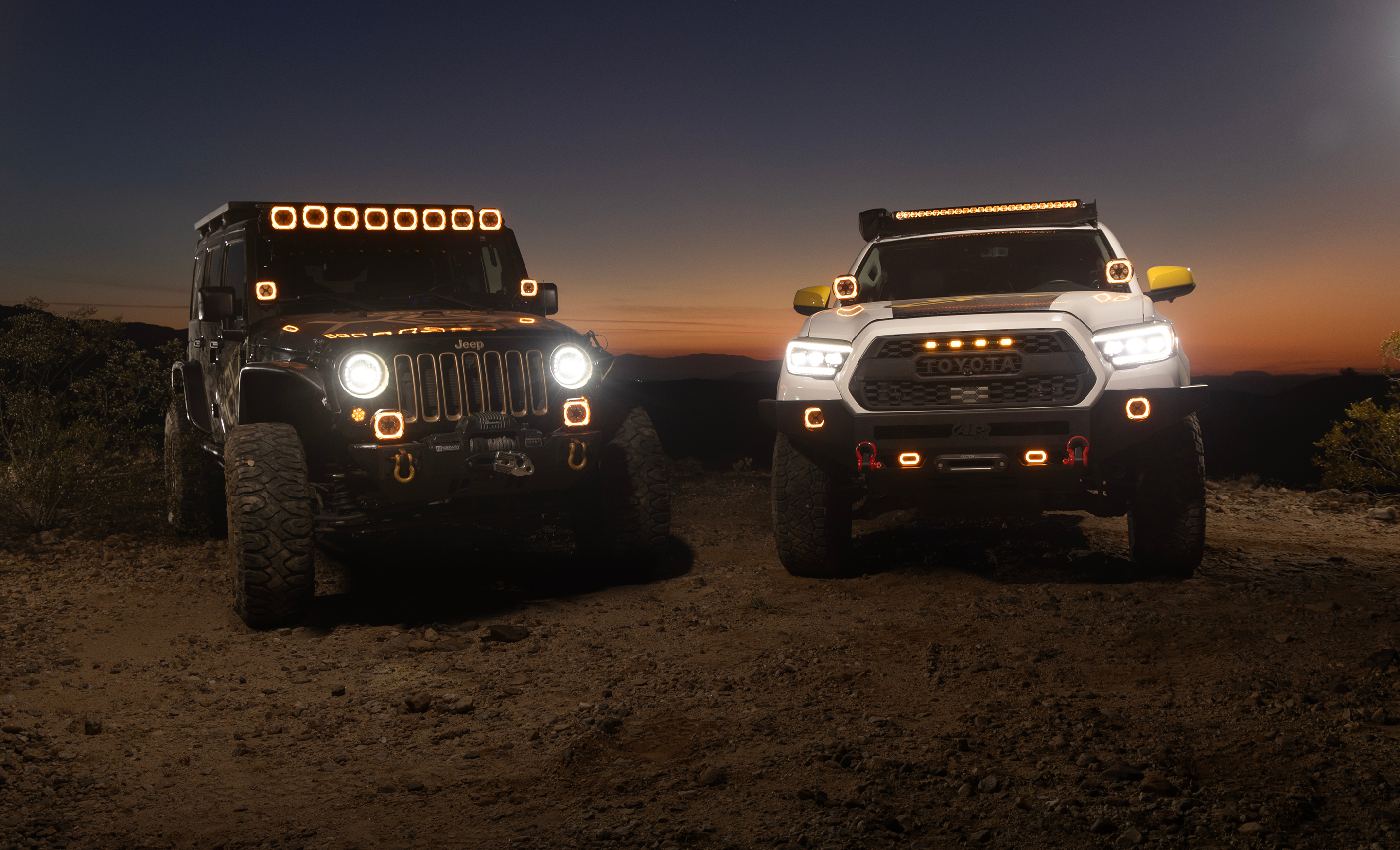 Two off-road vehicles on a dirt road at sunset.
