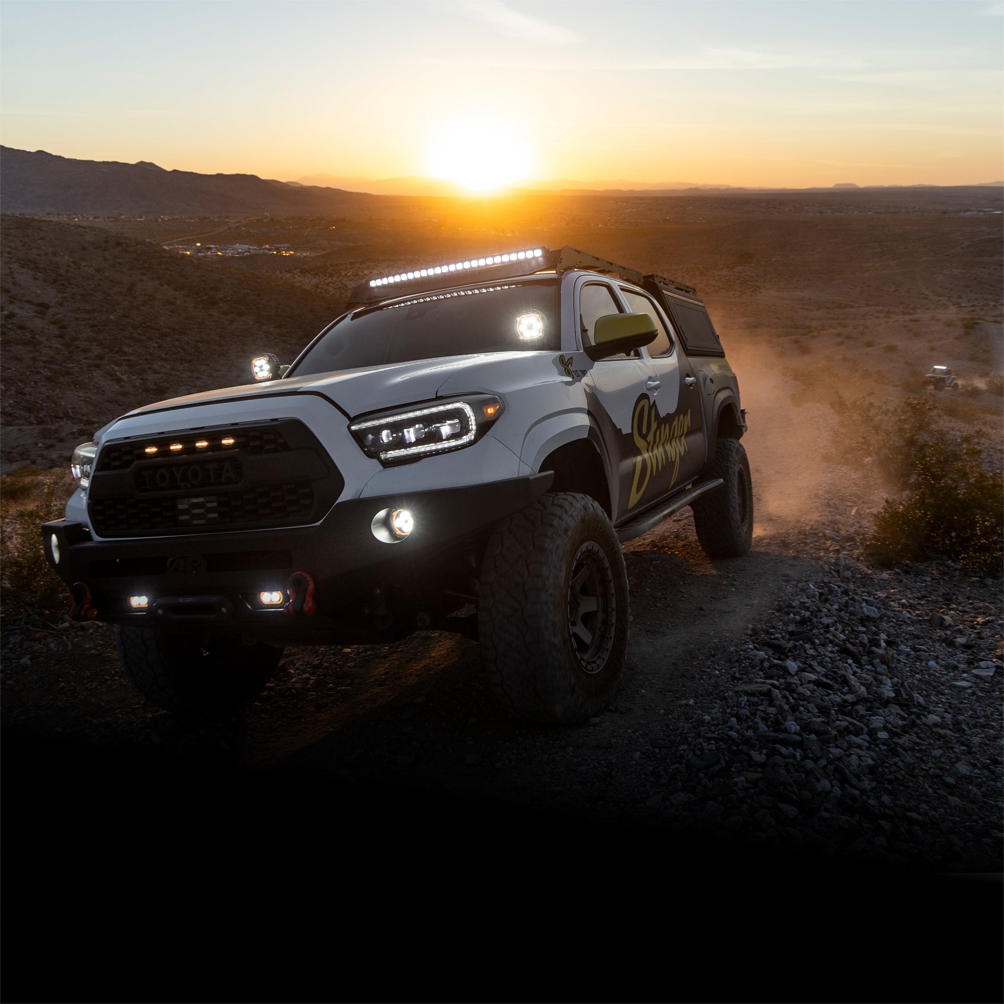 Off-road vehicle driving on a dirt road with a sunset in the background