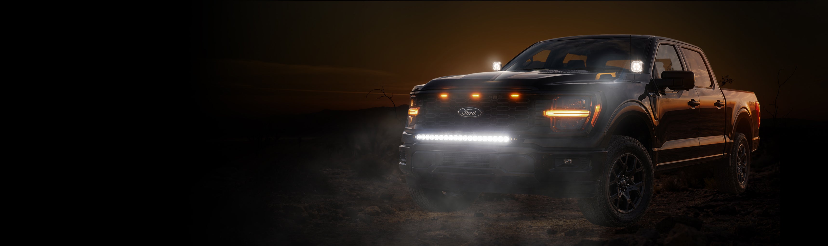 Dark pickup truck with illuminated headlights on a dark background