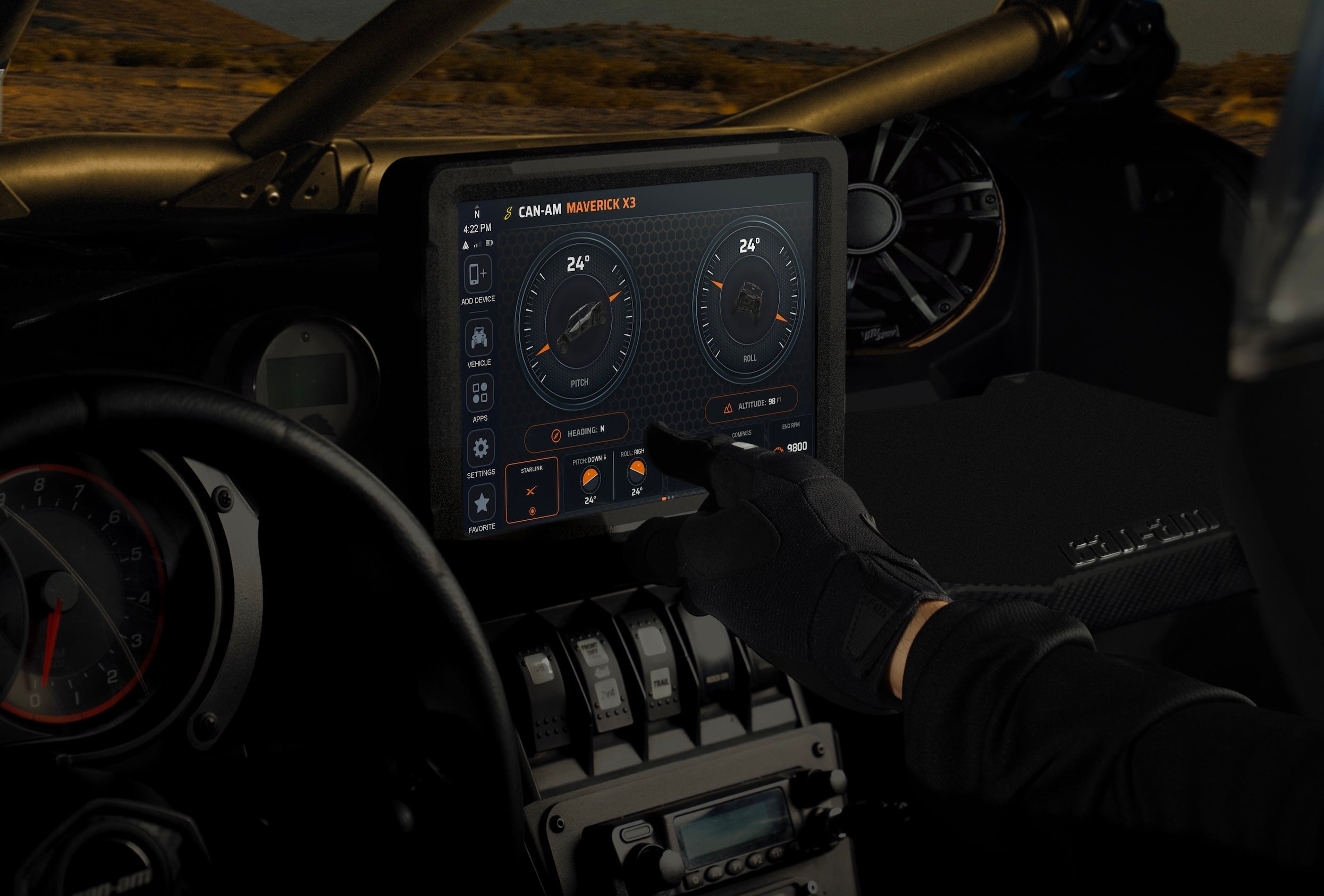 Gloved hand touching Can-Am Maverick X3 digital dashboard display showing vehicle pitch and roll data