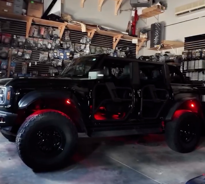 Black off-road vehicle with red lights in a garage setting