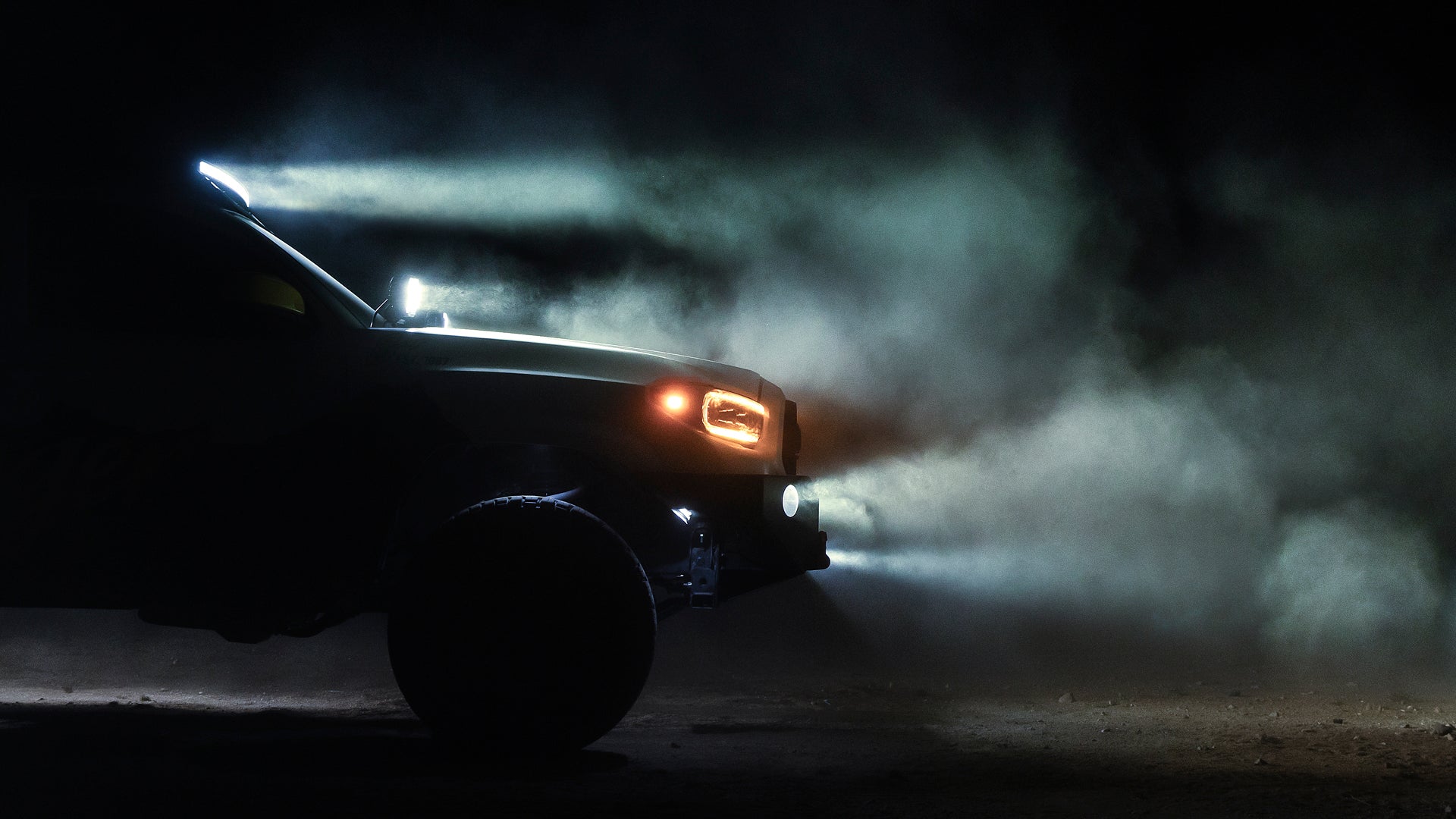 Off road truck with illuminated LED light bars and headlights in dark dusty conditions