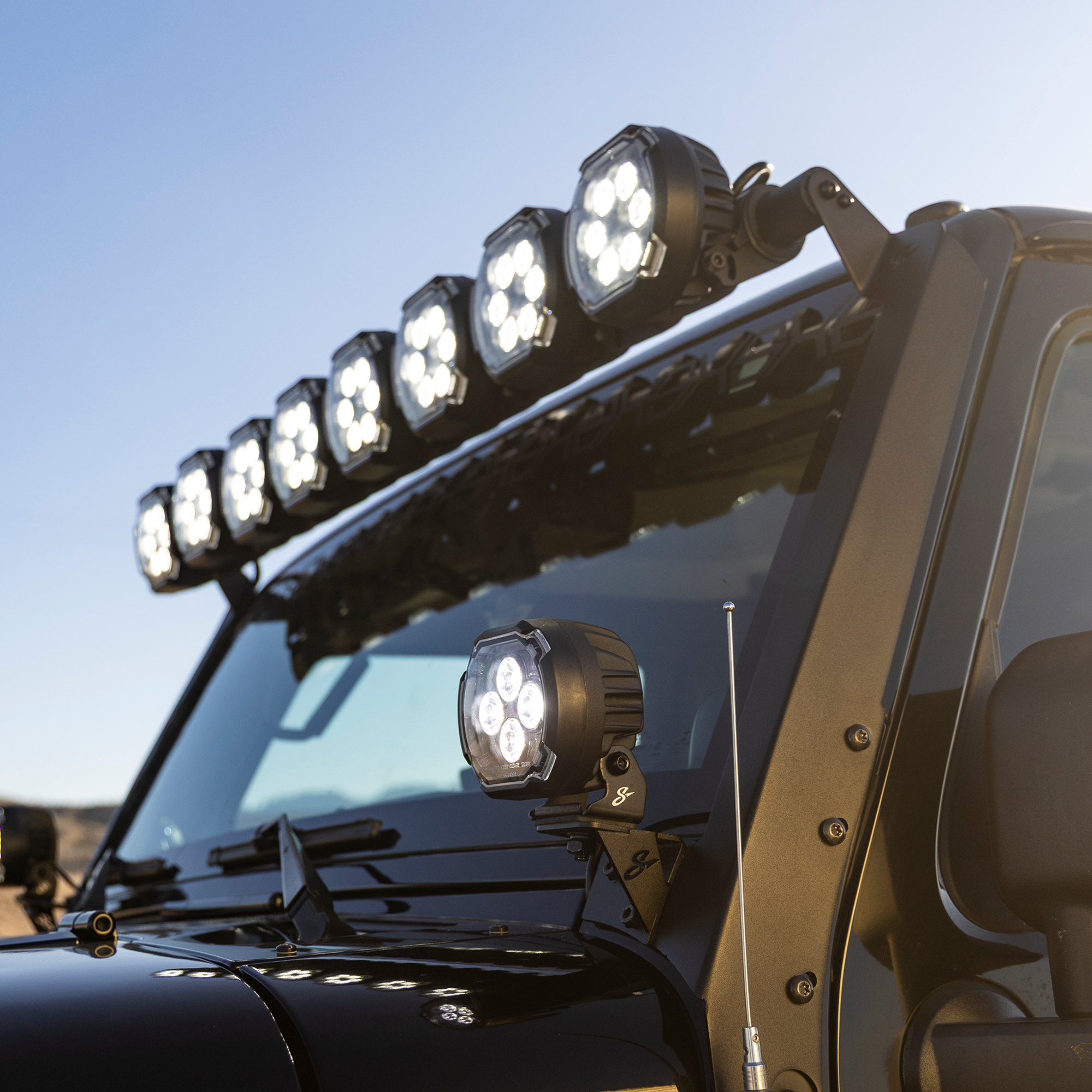 Black off-road vehicle with roof mounted LED light bar and pillar mounted auxiliary lights