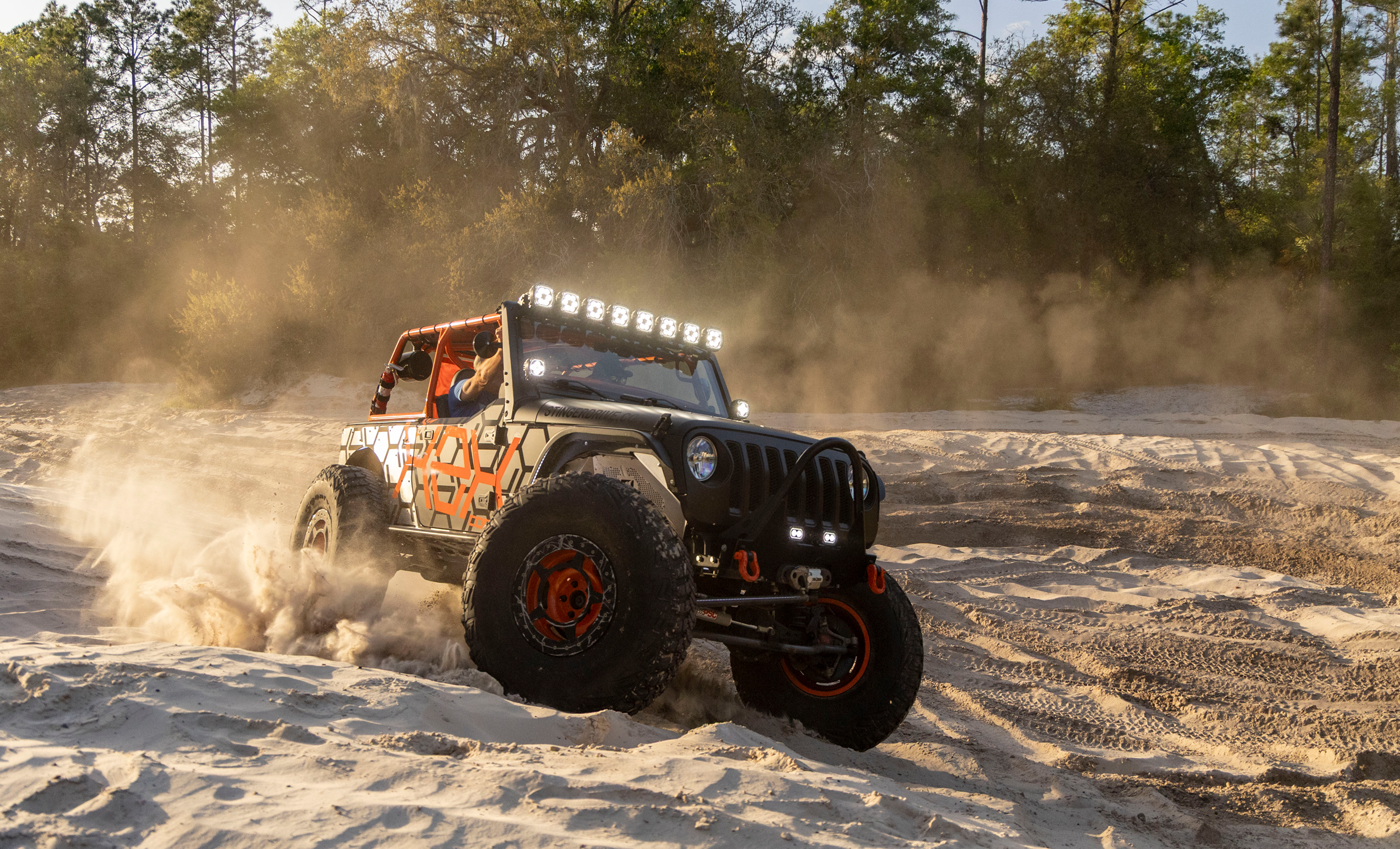 Off-road vehicle driving on a sandy terrain with dust in the air
