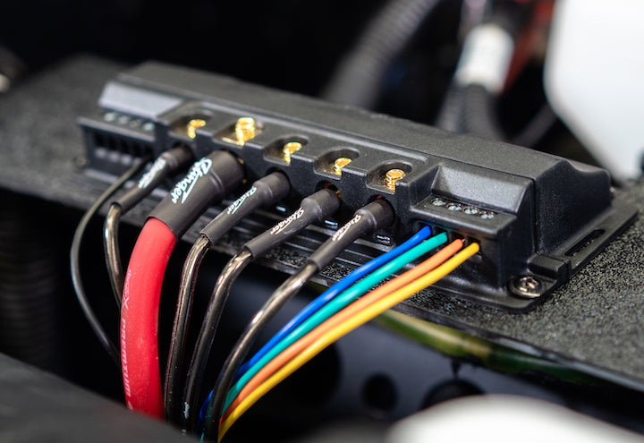 Close-up of a wiring harness with colored wires and connectors on a dark background