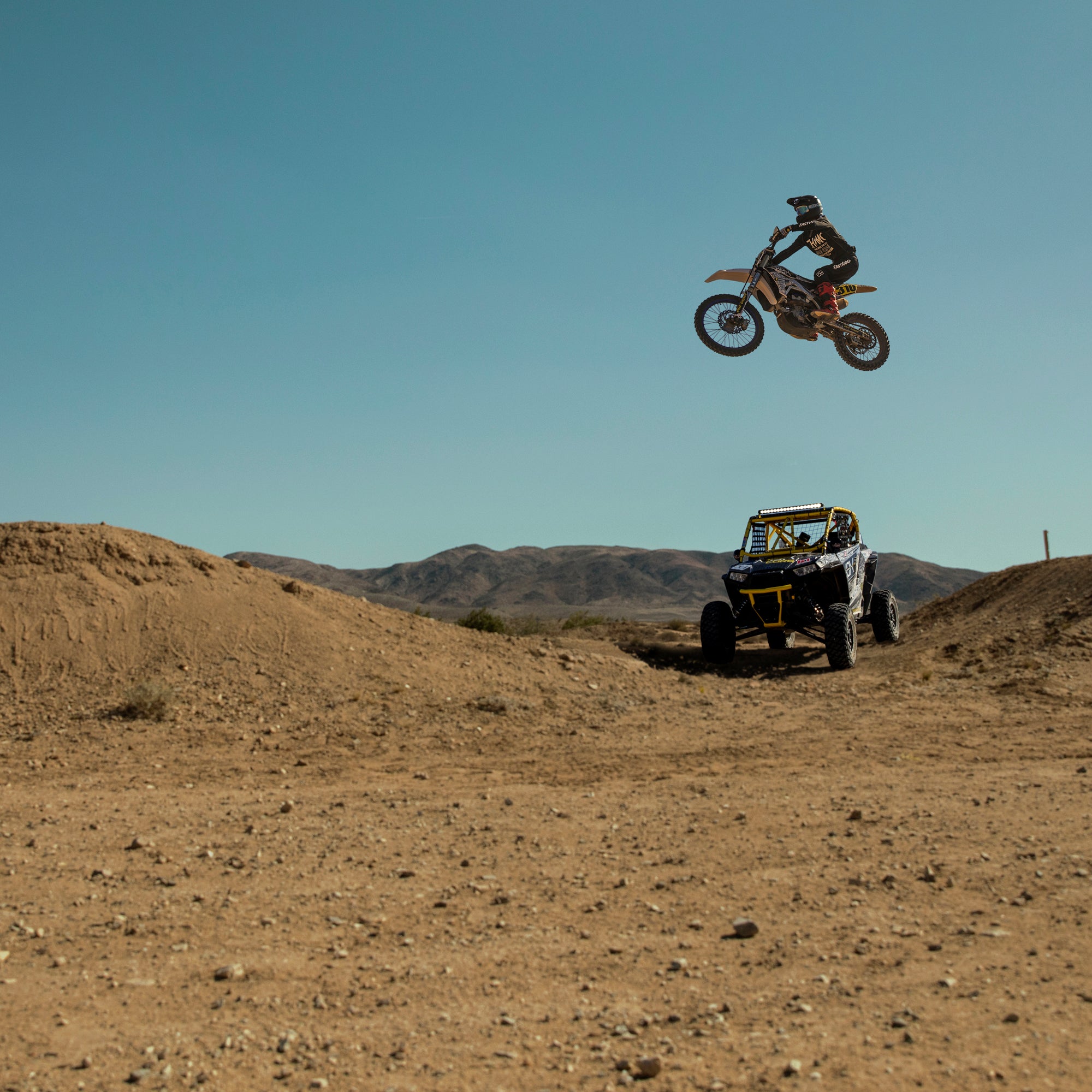 Motocross rider jumping over a UTV in the desert