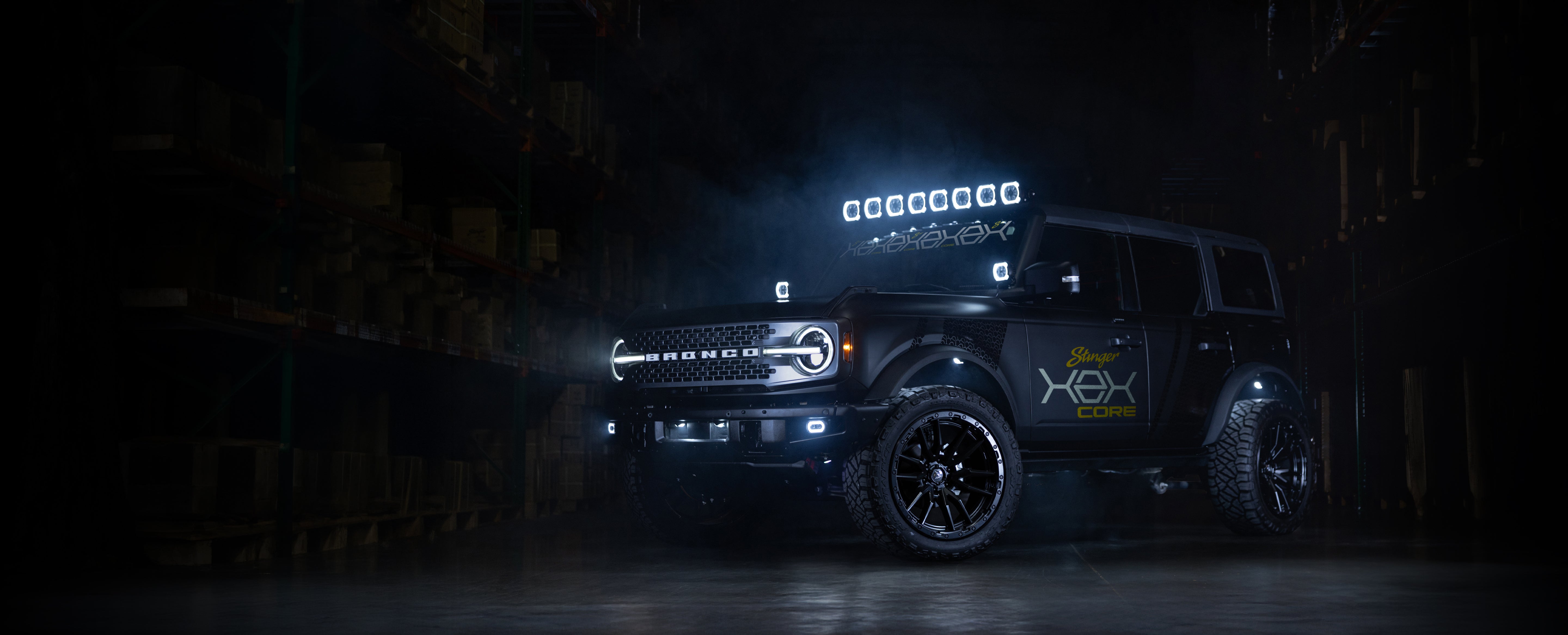 Black Ford Bronco with off road lights and custom decals in a dark warehouse