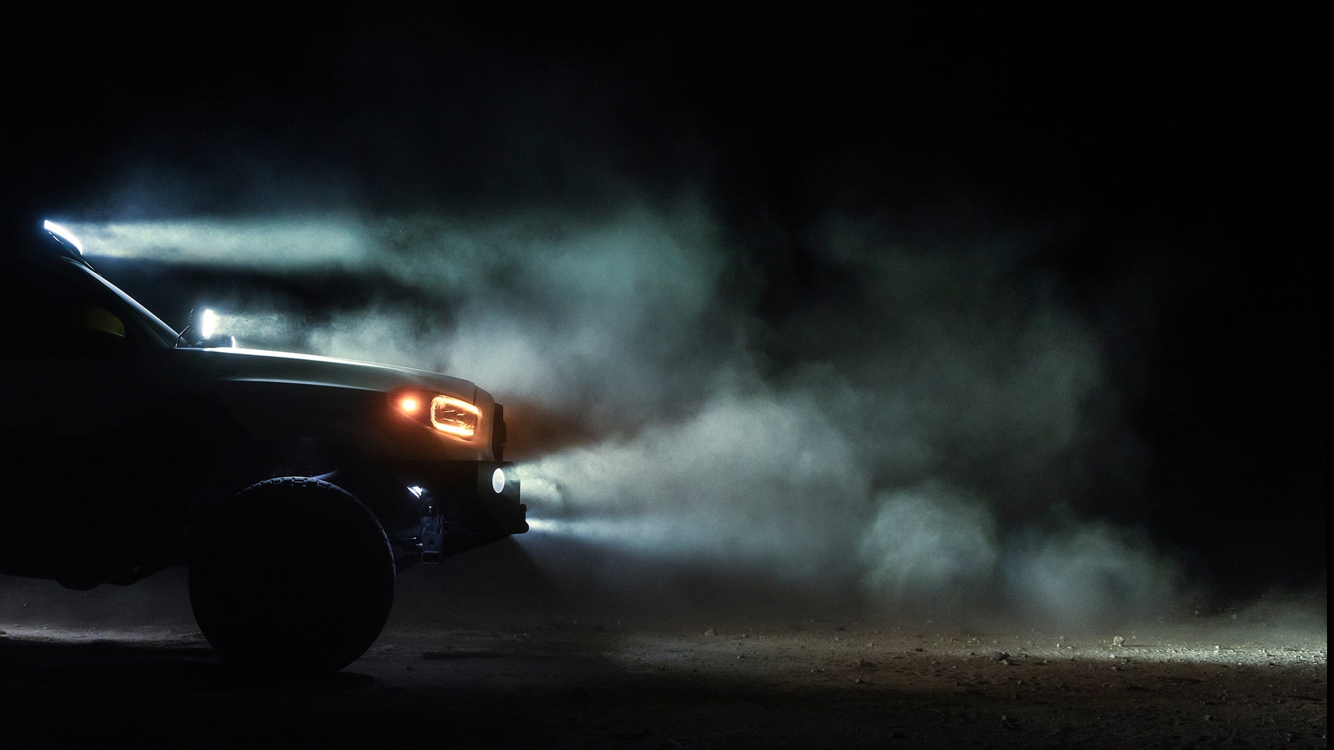 Car driving on a dirt road with smoke in a dark setting