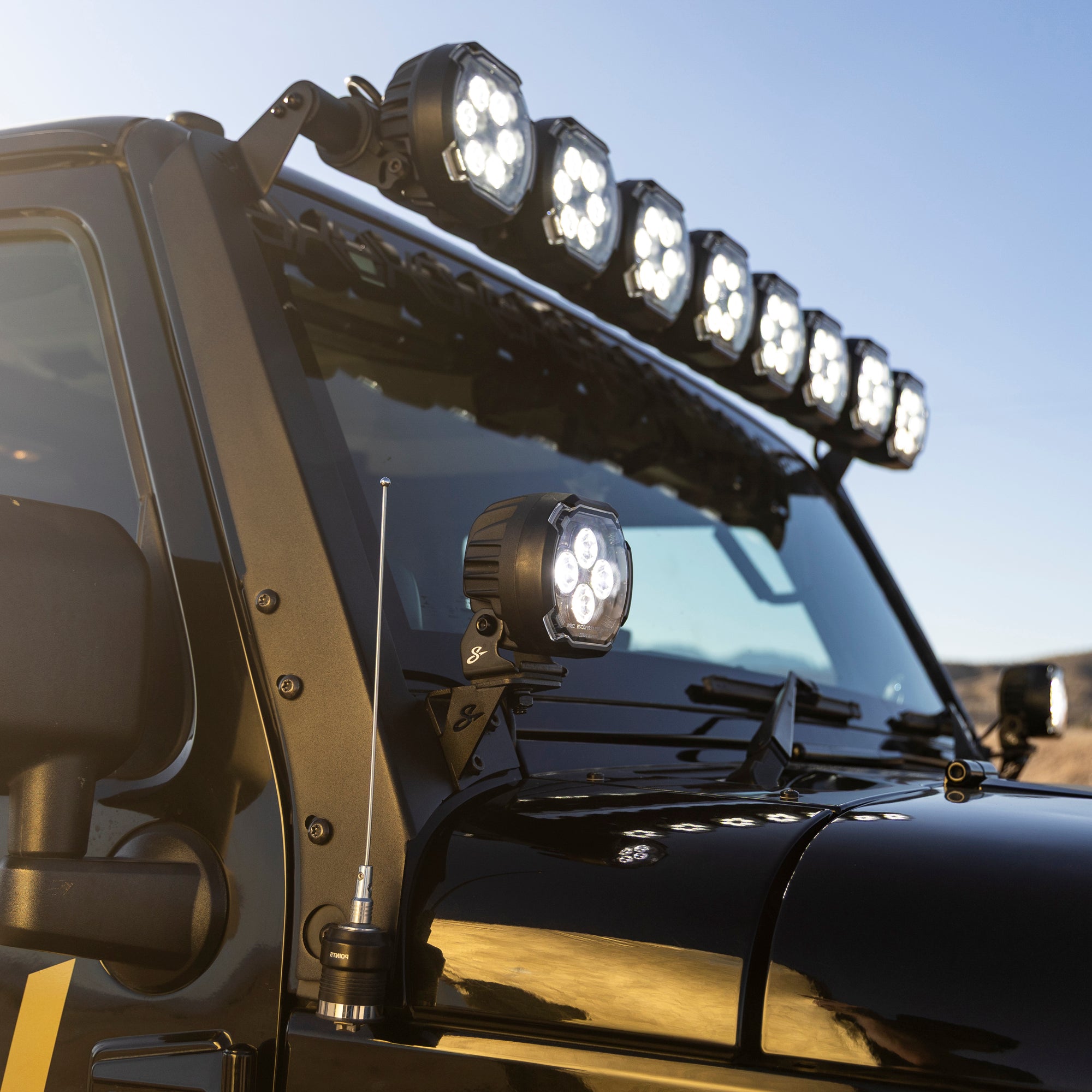 Offroad vehicle windshield with roof mounted LED light bar and pillar mounted auxiliary lights