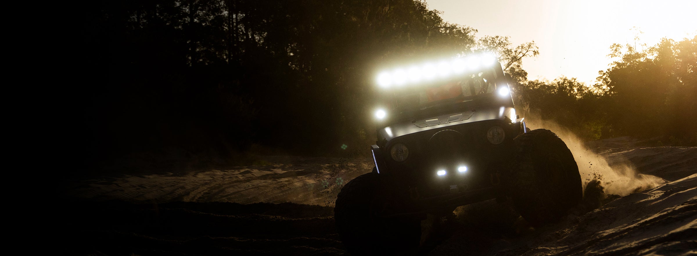 Monster truck on a dirt road with headlights on at night