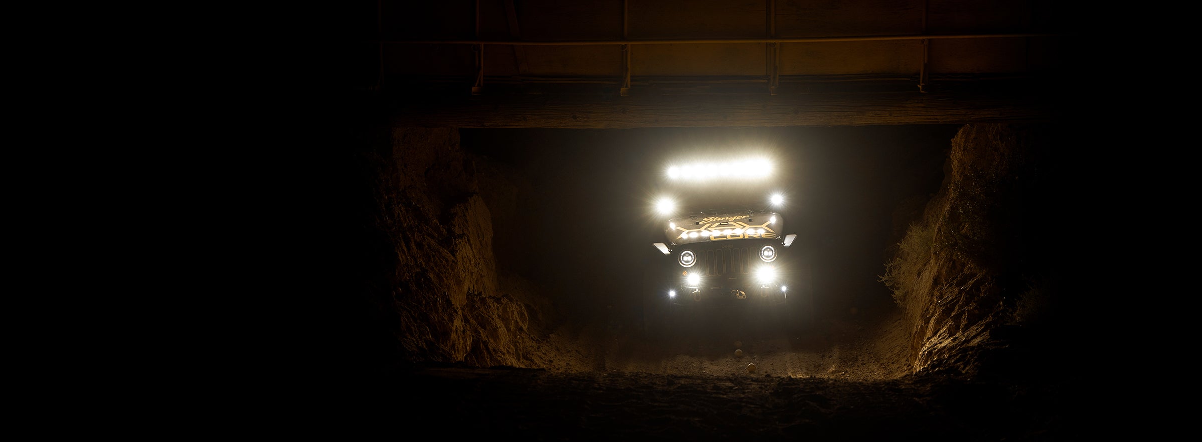 Truck inside a dark tunnel with bright headlights illuminating the path.