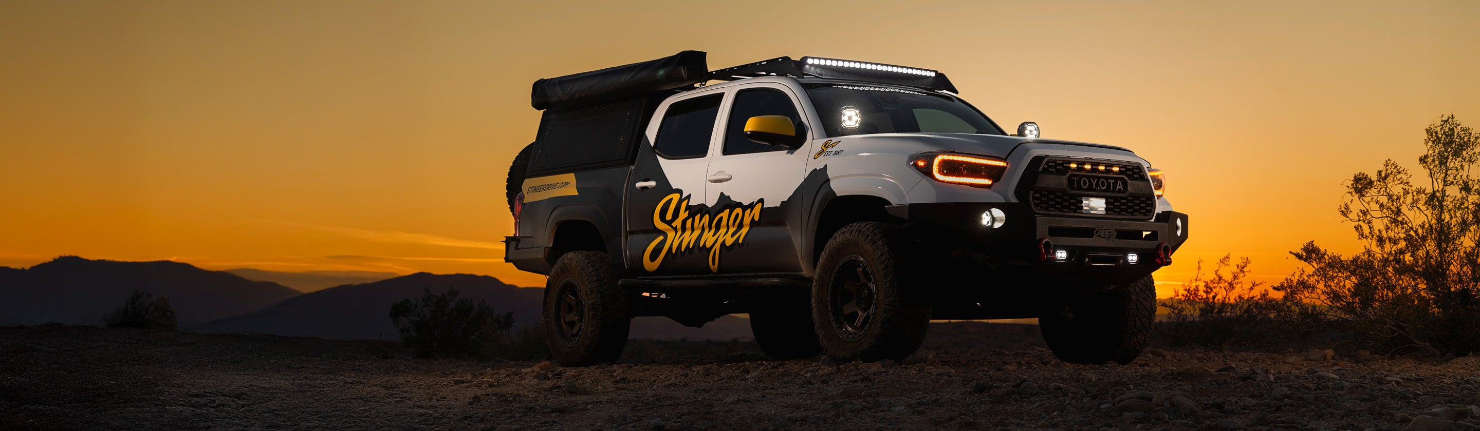 Truck with 'Stinger' branding on a desert landscape at sunset