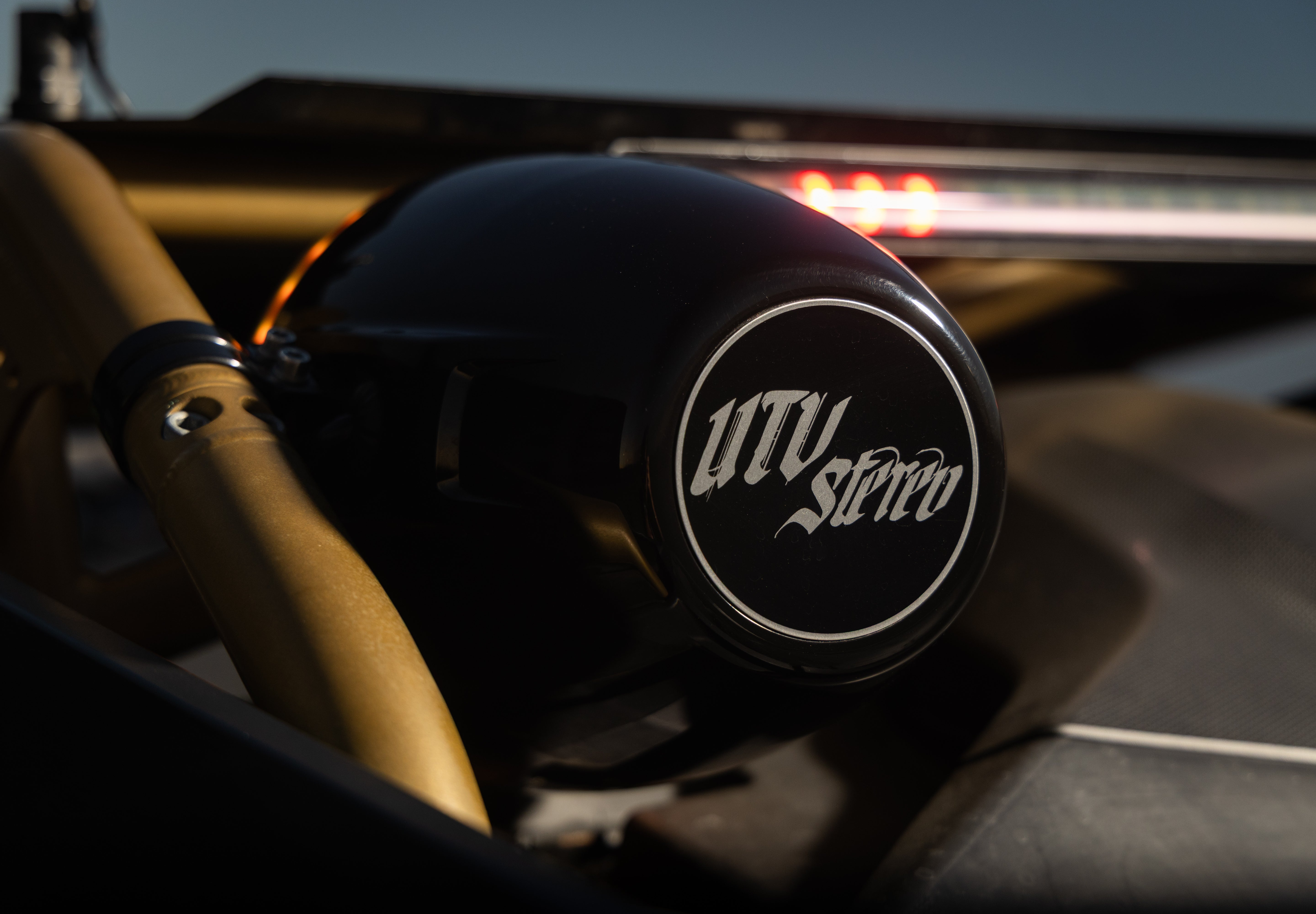 Black UTV Stereo speaker pod mounted on a gold roll cage