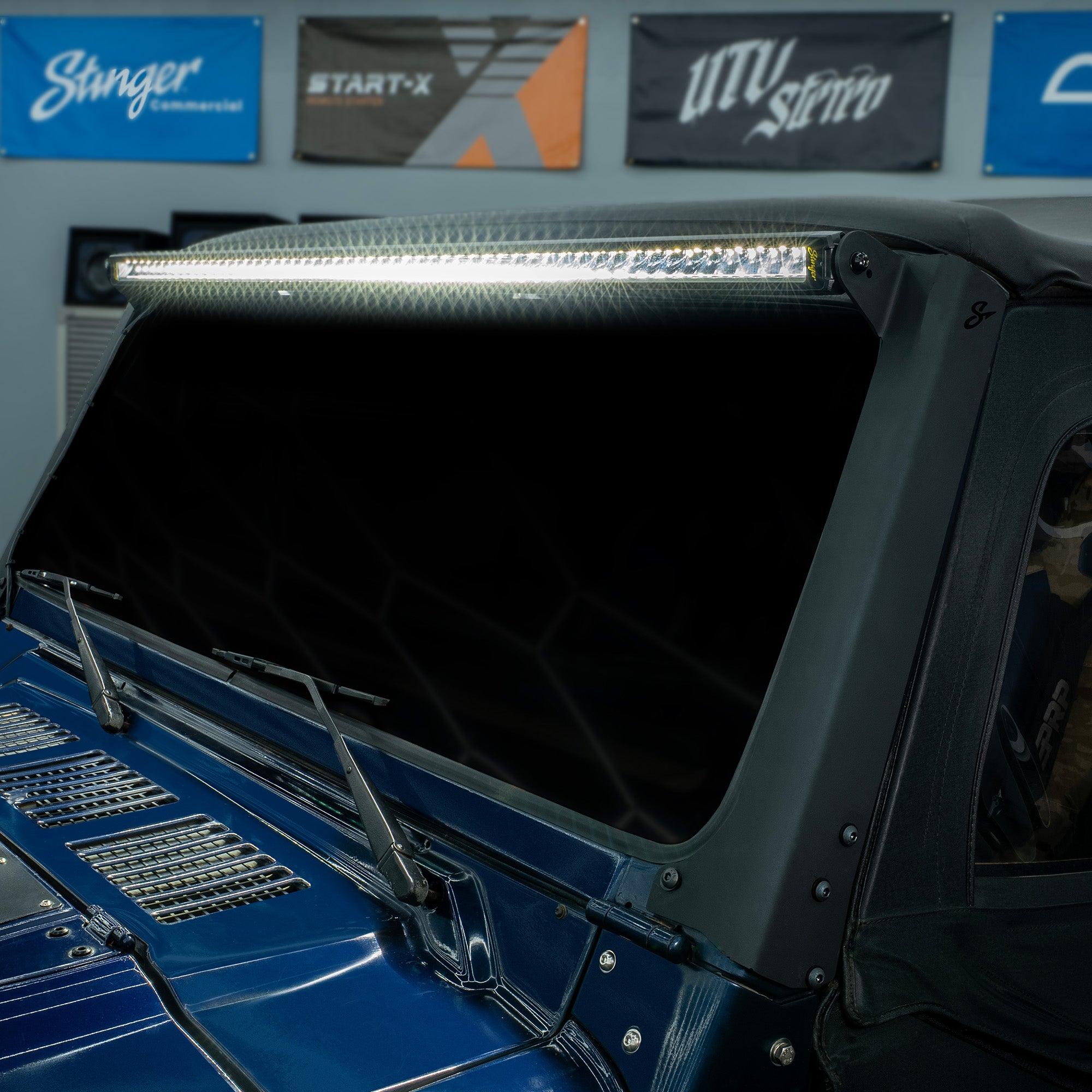 Stinger LED light bar mounted above the windshield of a blue vehicle