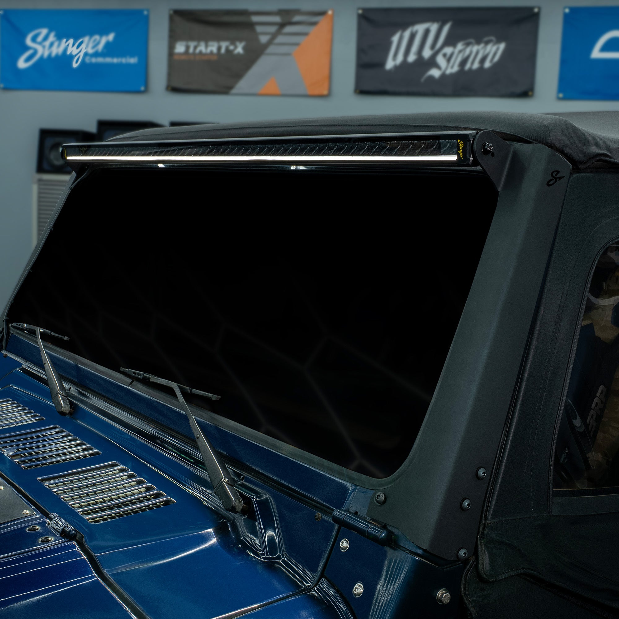 Stinger LED light bar mounted above the windshield of a blue vehicle