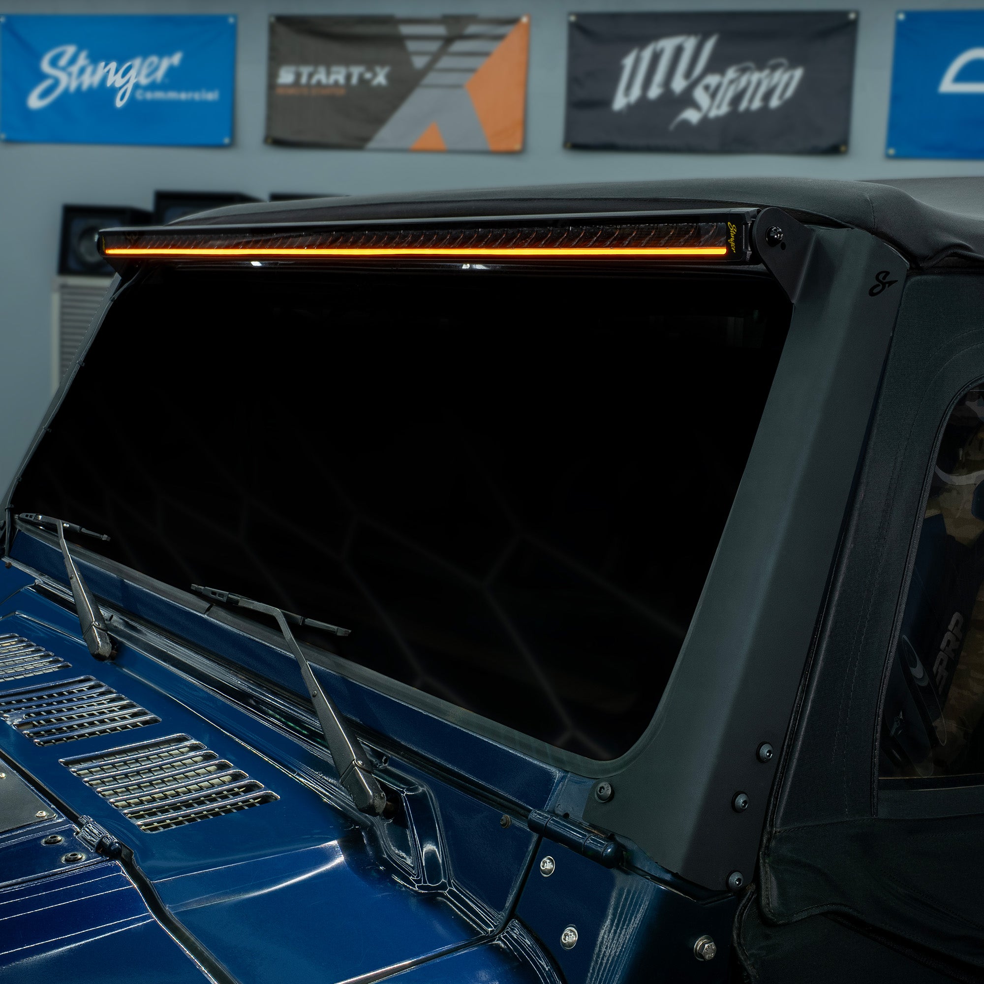 Stinger LED light bar mounted above the windshield of a blue vehicle