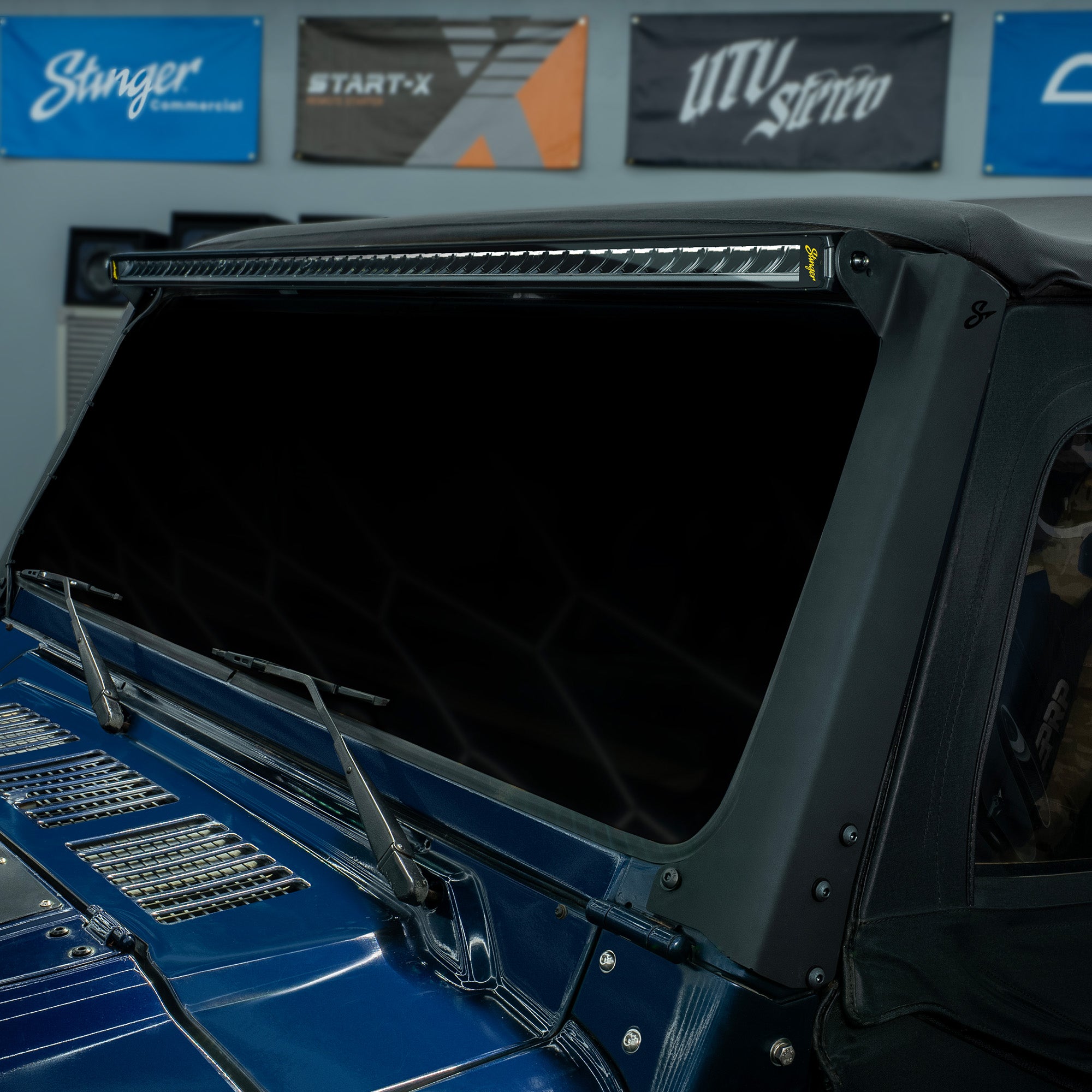 Stinger LED light bar mounted above the windshield of a blue vehicle