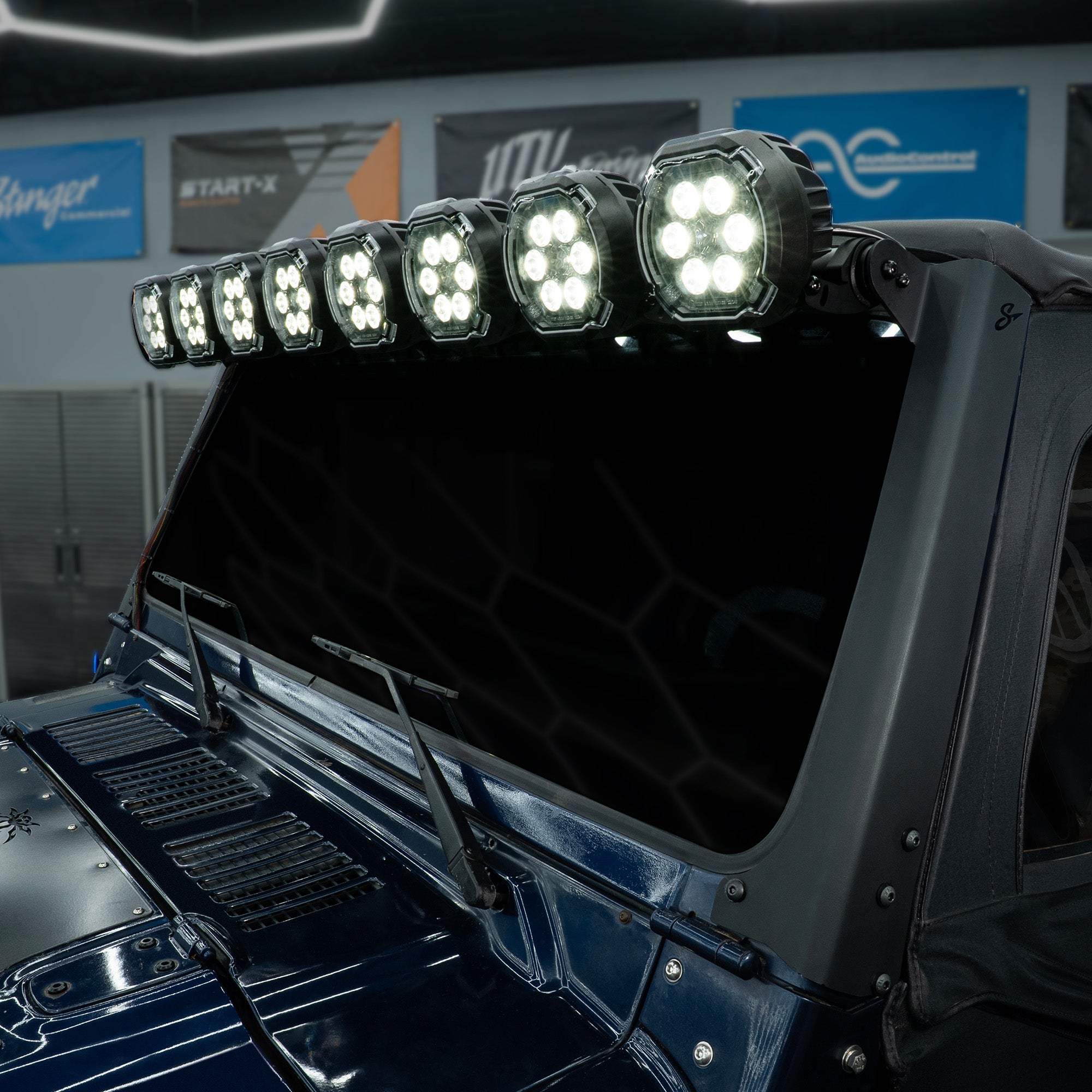 Stinger LED light bar mounted above the windshield of a dark blue vehicle
