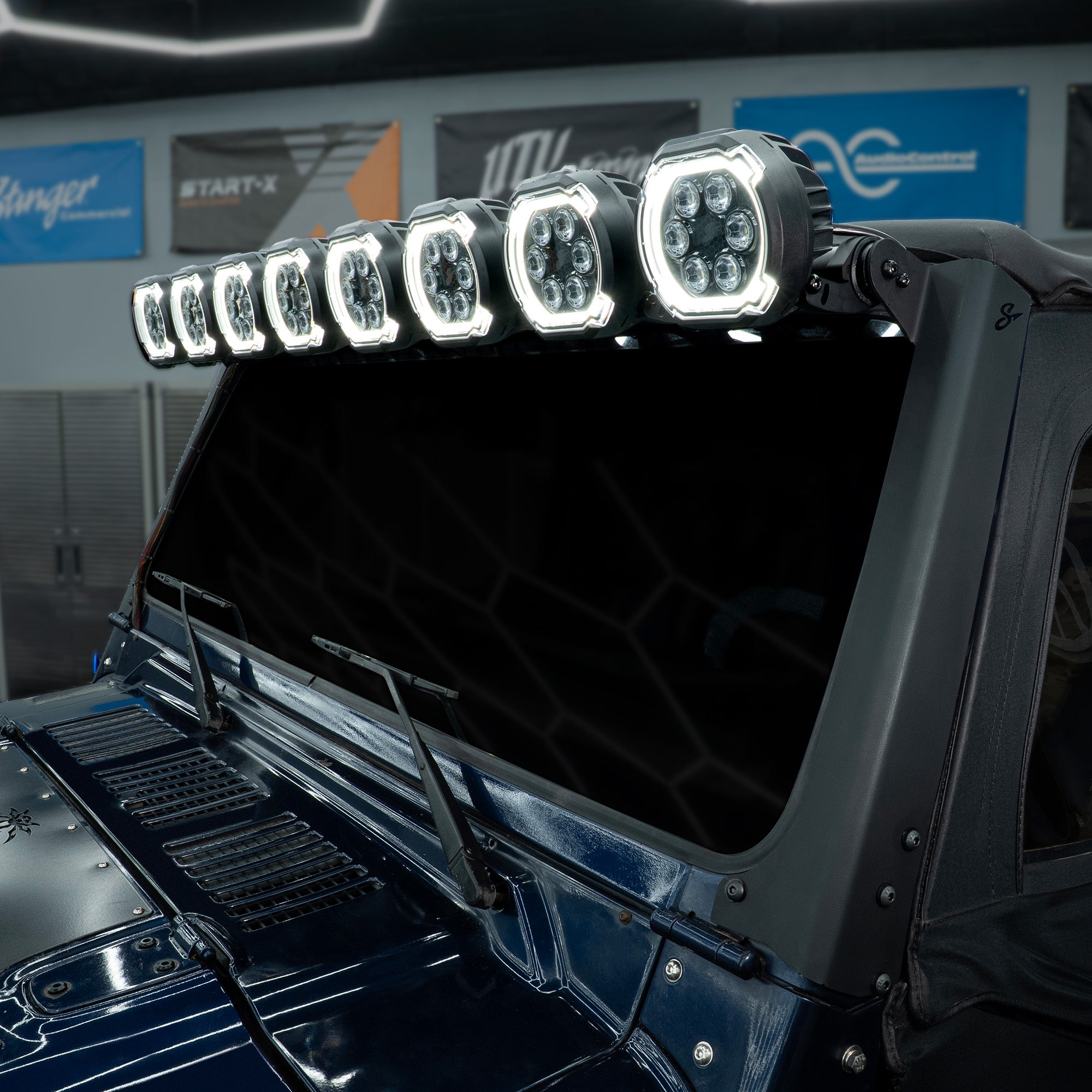 Stinger LED light bar mounted above the windshield of a dark blue vehicle