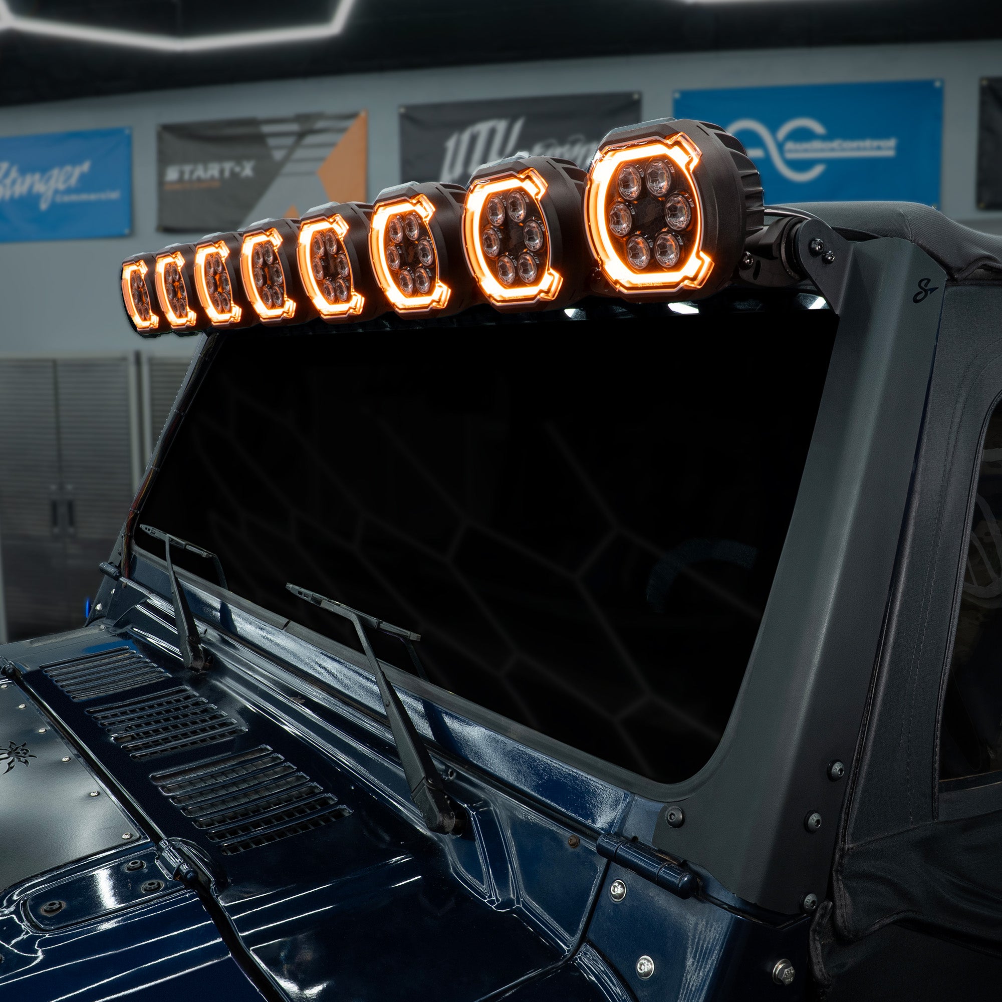 Stinger LED light bar mounted above the windshield of a dark blue vehicle