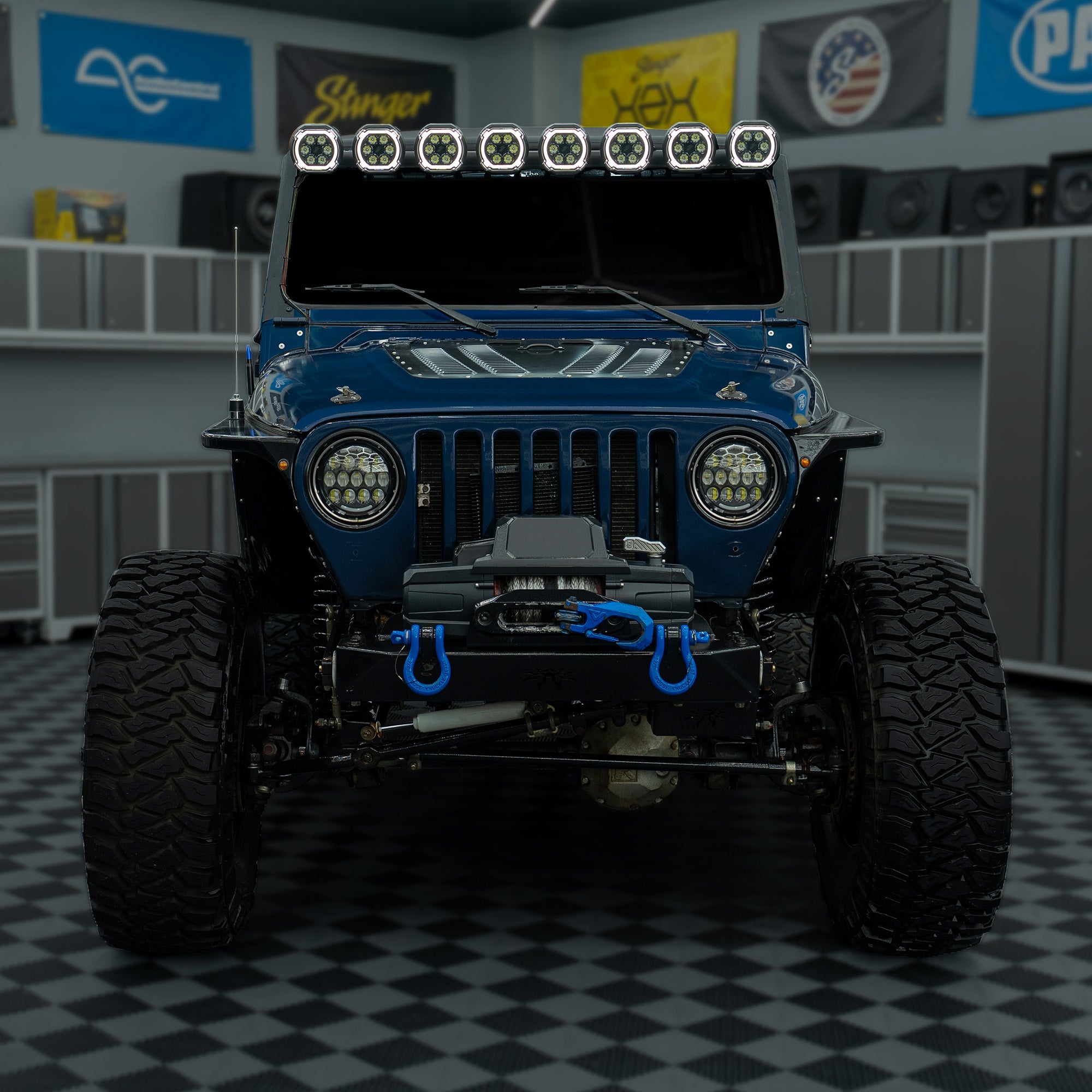 Blue Jeep with Stinger LED light bar and off-road winch in a garage