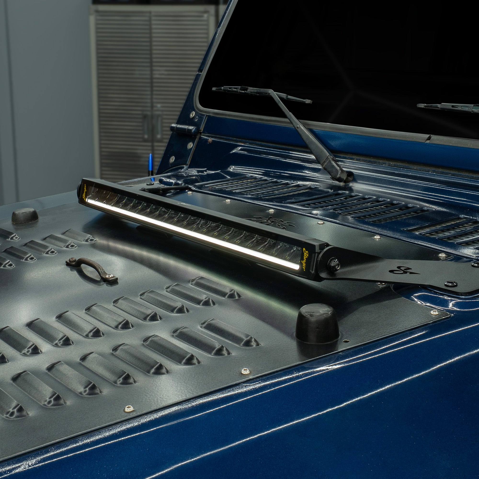 Stinger LED light bar mounted on the hood of a blue Jeep