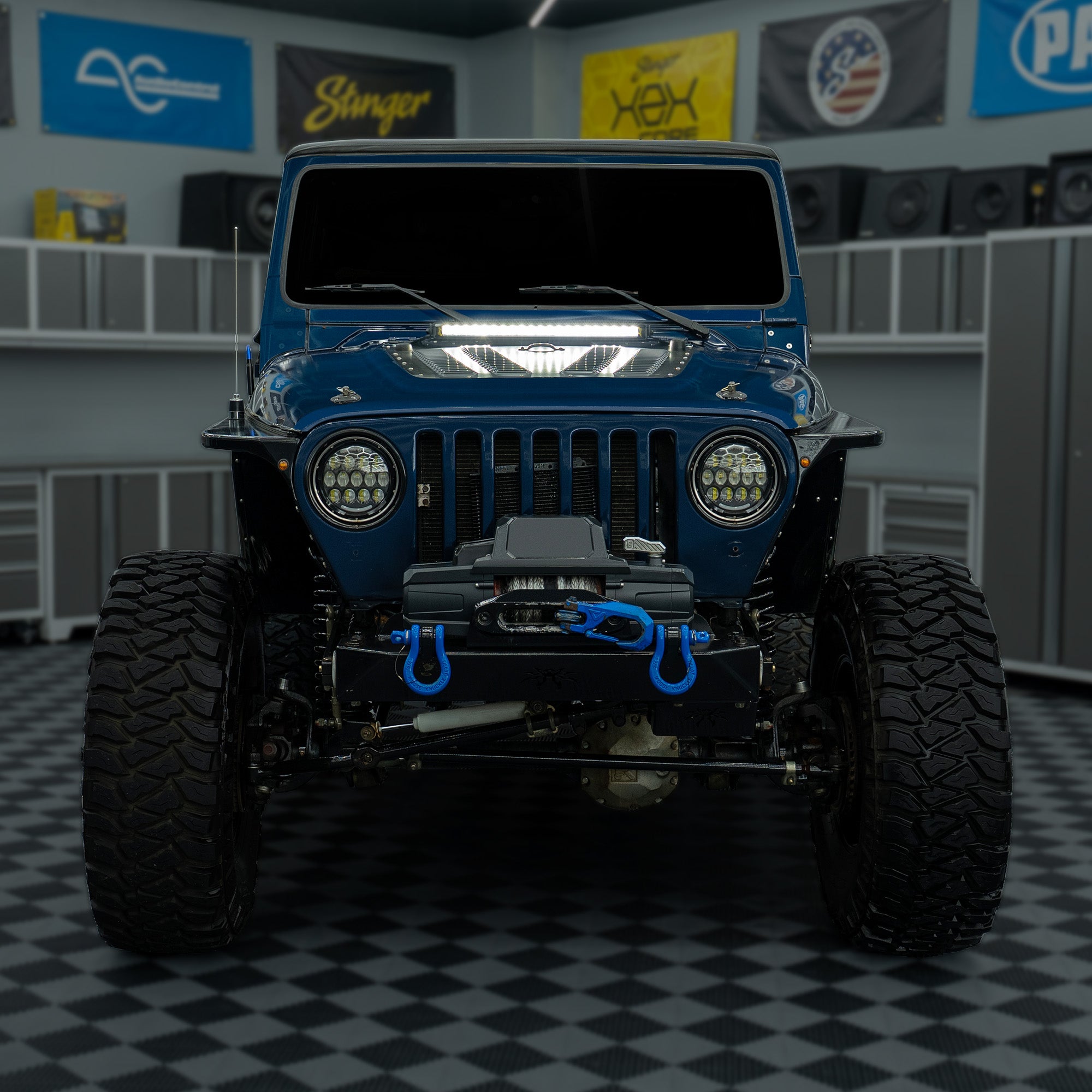 Front view of a blue Jeep with Stinger off road equipment in a garage