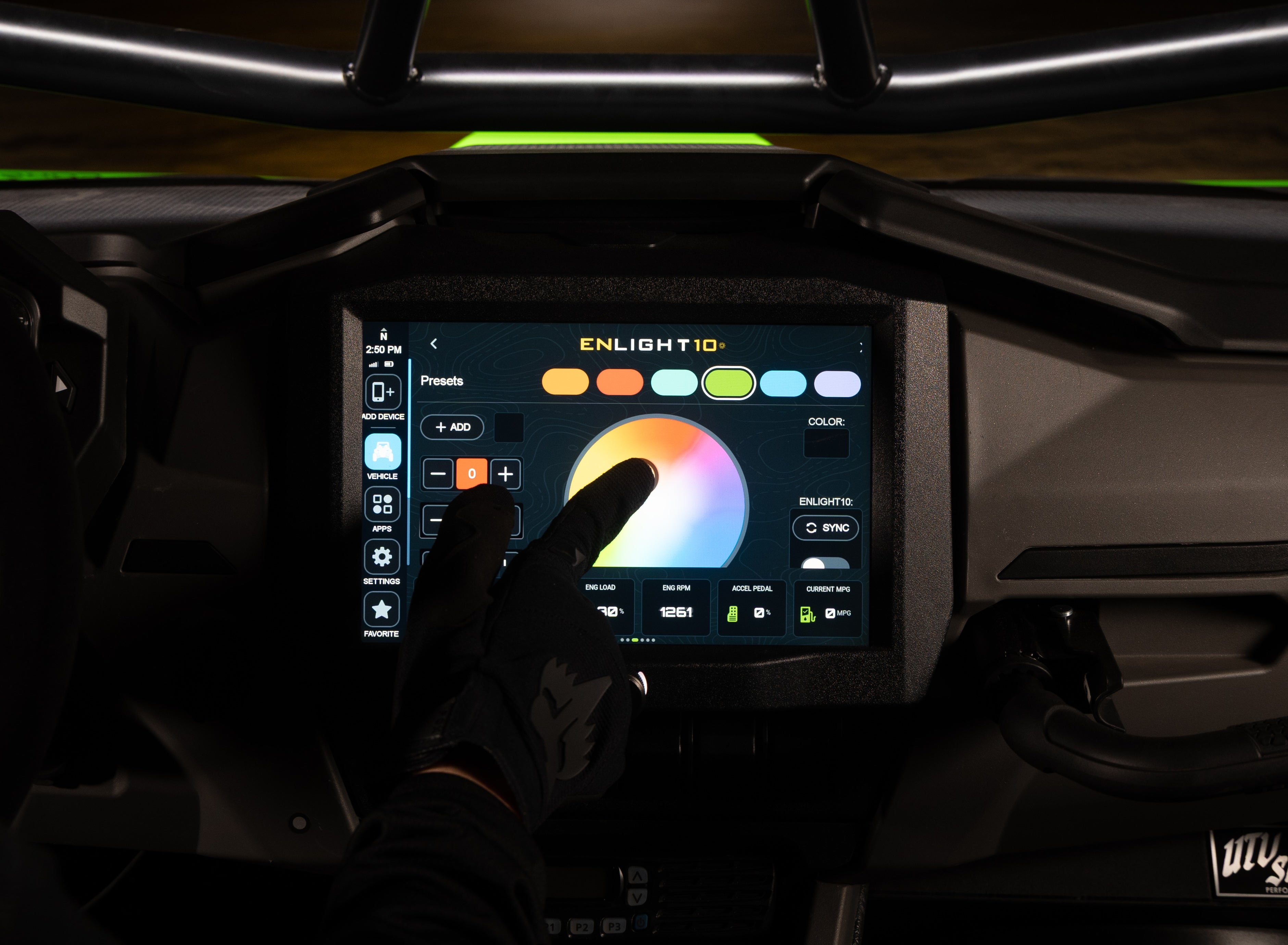 A close-up of a vehicle's digital dashboard display showing the Enlight 10 color lighting system interface, with a gloved hand touching the screen to adjust the lighting color.