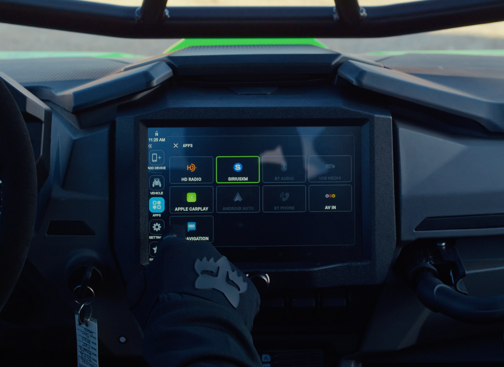 Gloved hand touching the digital touchscreen display in a vehicle dashboard showing app icons
