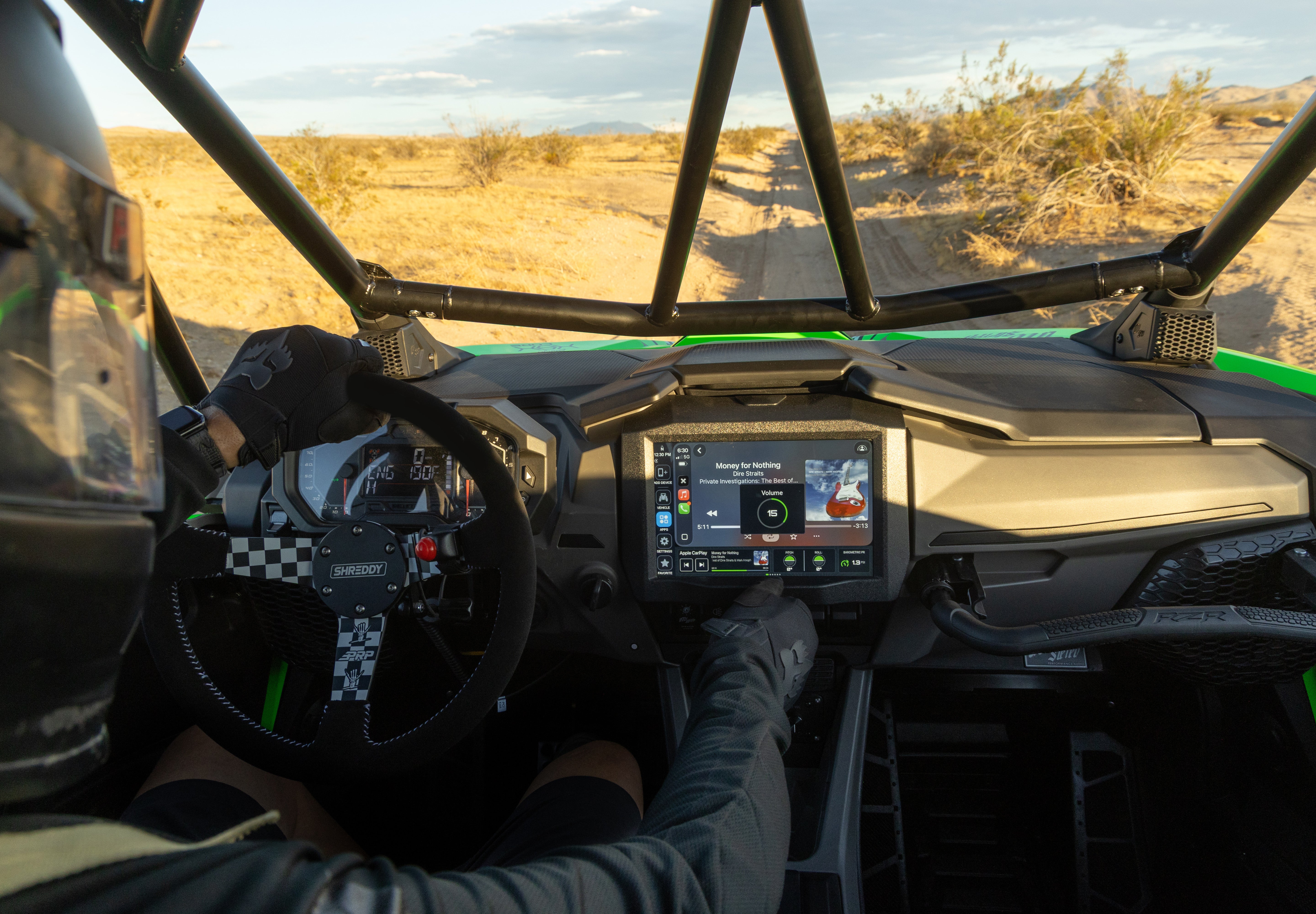 Driver in helmet operating a touchscreen display inside a UTV on a desert trail