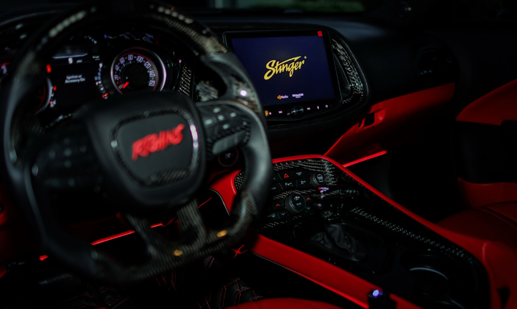Car interior with steering wheel and dashboard display, featuring 'FDK' and 'Stinger' branding.